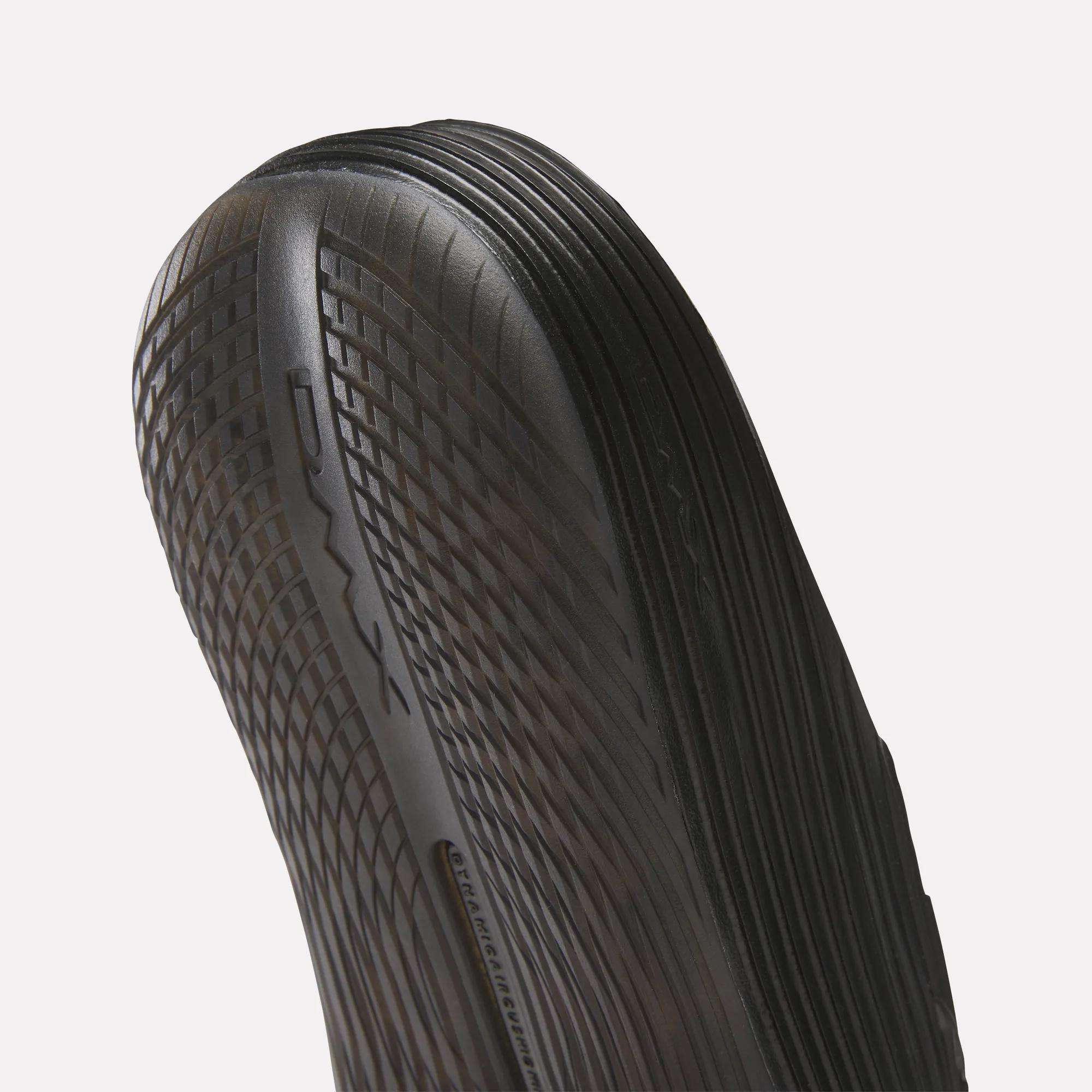 Close-up of the black, textured sole on Reebok DMX Recovery Walking Slides, showing DMX moving air cushioning along the side and detailed ridged patterns for enhanced grip.