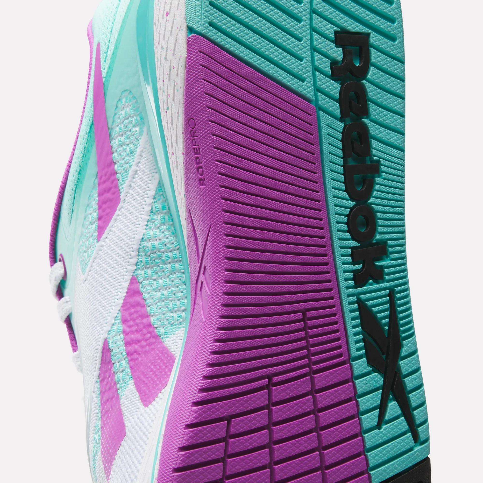 Close-up of the sole on Reebok Nano X5 Training Shoes for men, showcasing teal and purple tones, textured grip patterns, and a black Reebok logo.