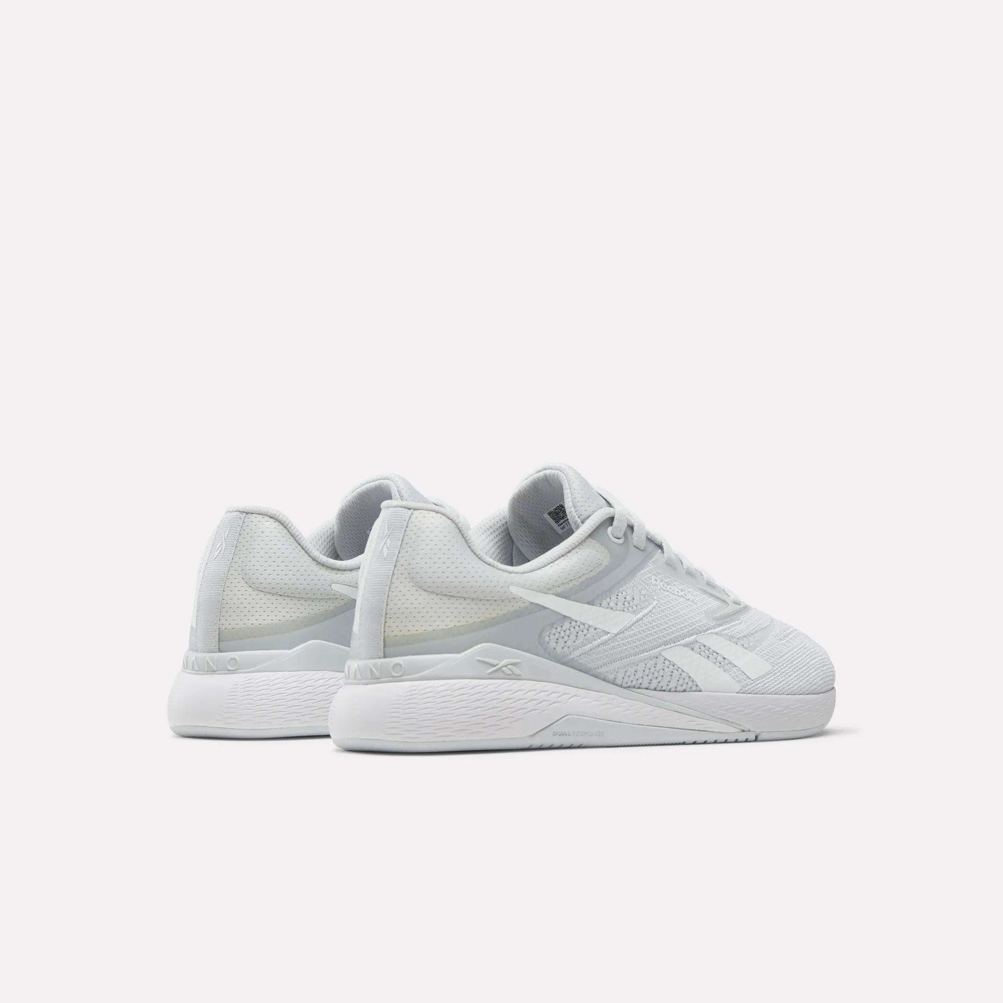 A pair of Reebok Women's Nano X5 Training Shoes in light gray with white soles and laces is shown on a plain white background, positioned to display both the side and back views.