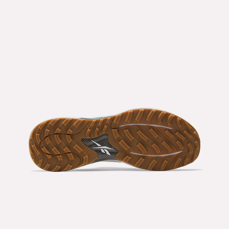 The image shows the bottom view of Reebok Nano Golf Shoes, featuring a textured brown rubber sole with a black center section displaying a white Reebok logo and lightweight FlexWeave technology for comfort and durability.