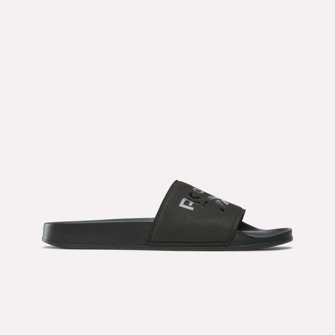 The Reebok RBK Fulgere Swim Slides are black slip-on sandals with a thick strap and bold white logo, displayed in profile against a plain white background.
