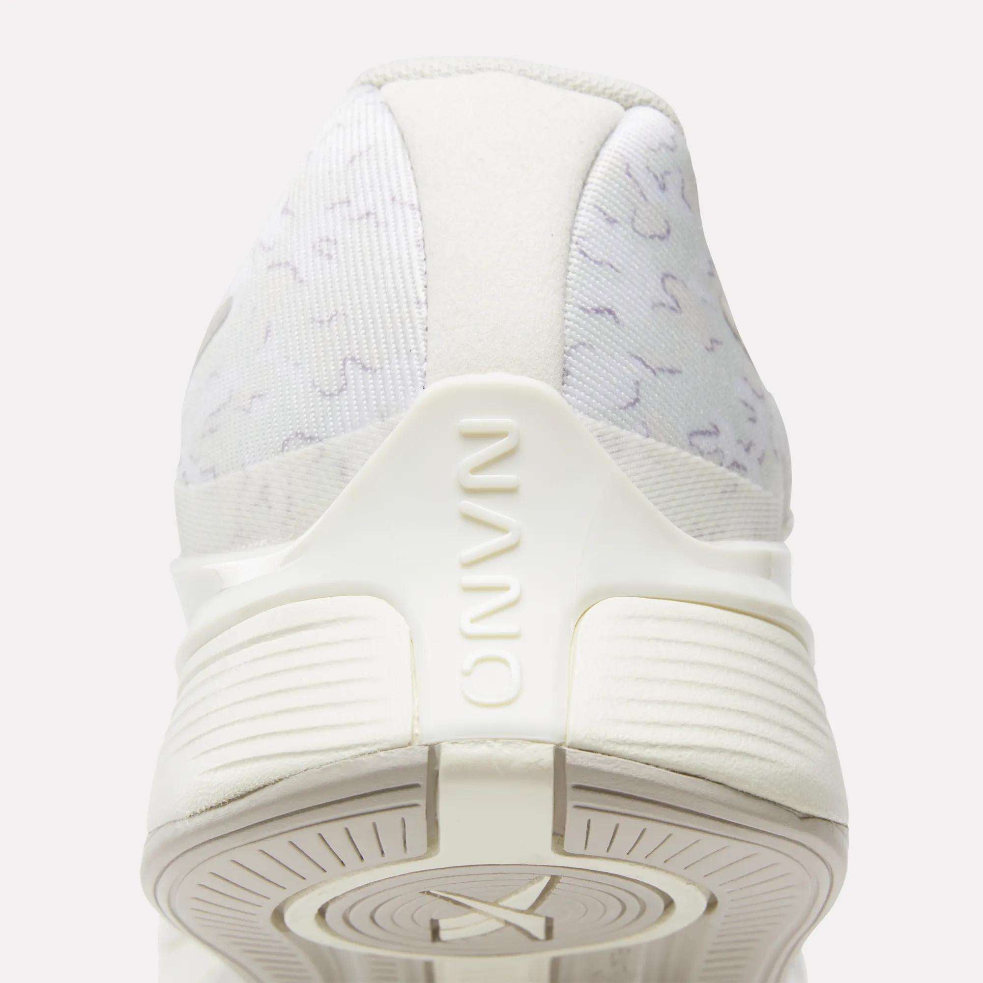 Close-up rear view of Reebok Nano X4 Training Shoes in white with subtle gray patterns, "NANO" embossed on the heel, and a textured sole. Lightweight, breathable features are visible at the bottom.