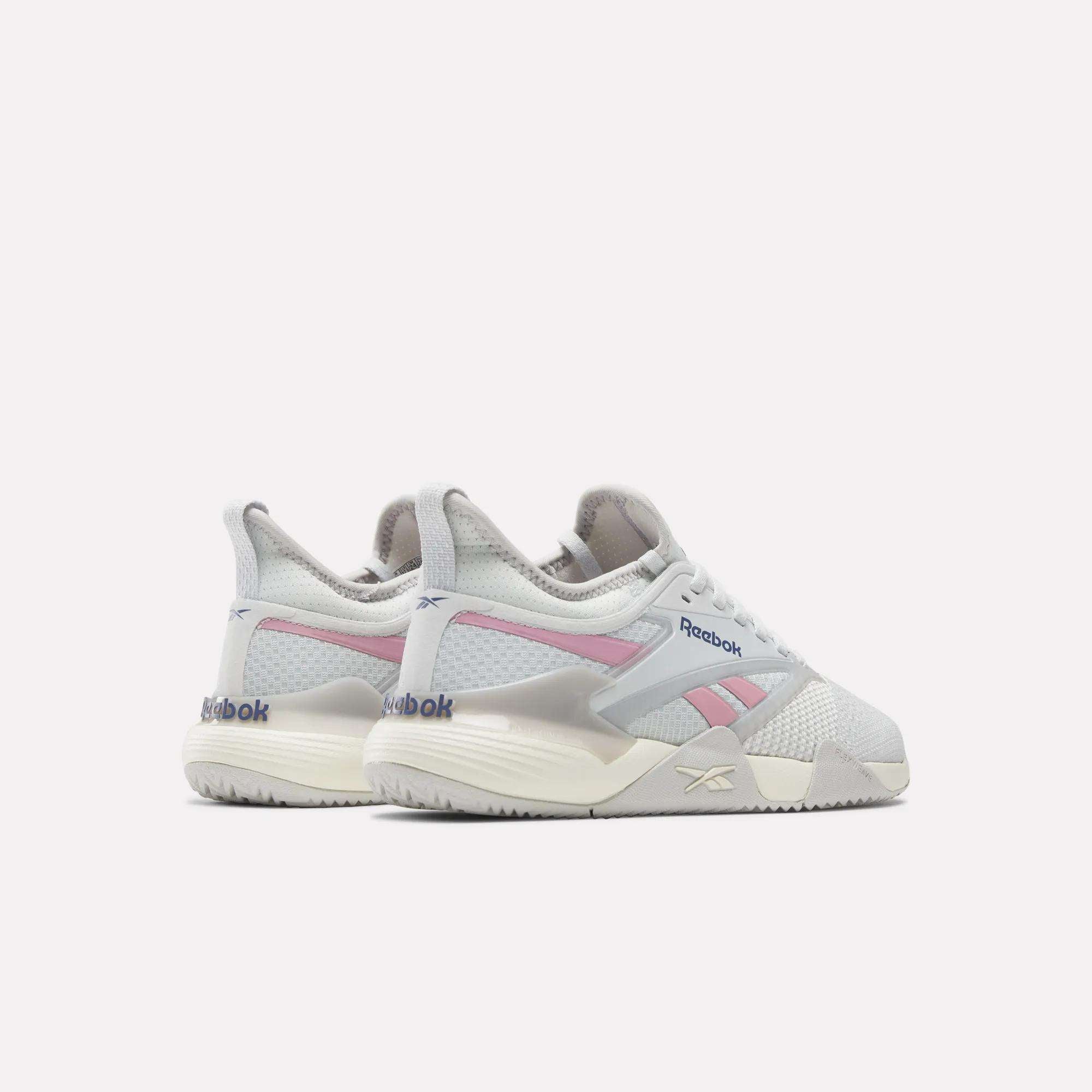 Reebok Women's Nano Court Training Shoes in white and light grey with pink and purple accents, shown from back and side angles, featuring a Griptonite rubber outsole on a plain white background.