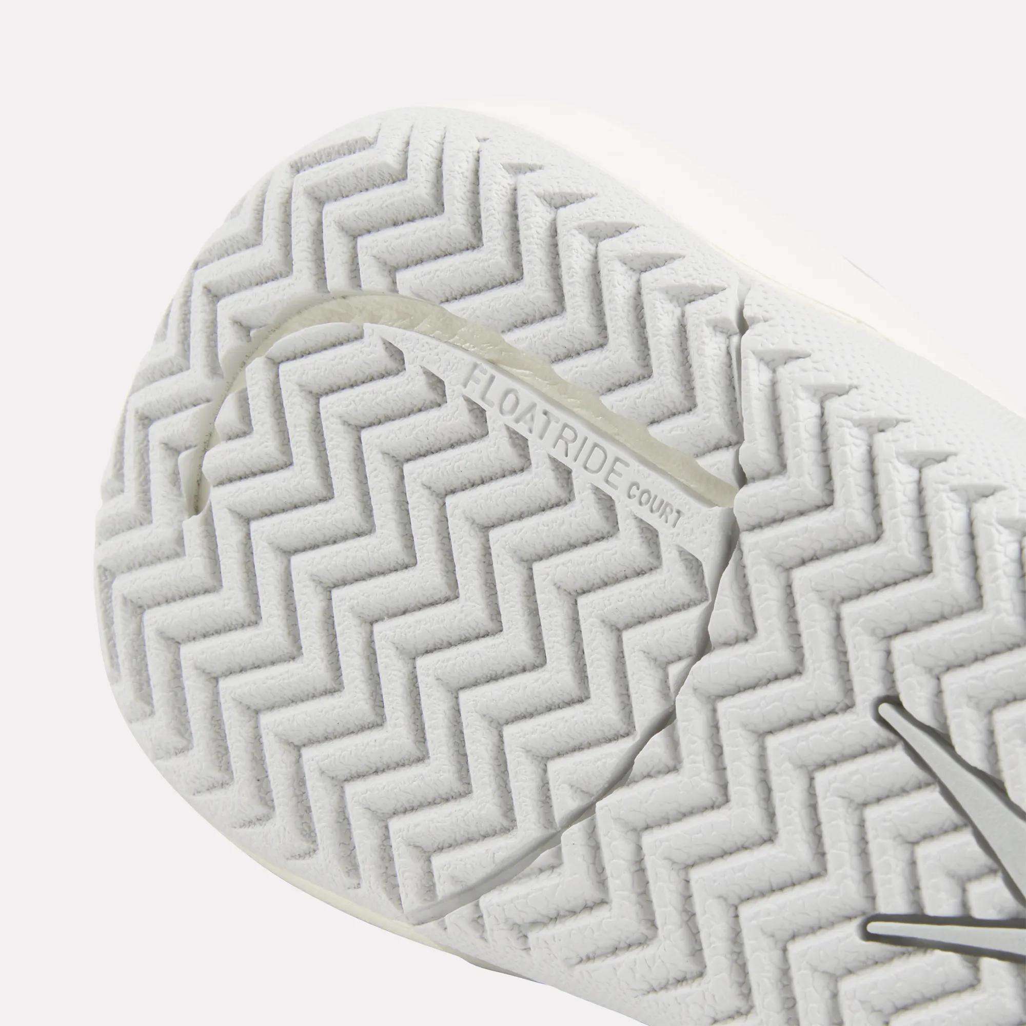 Close-up of the white sole on Reebok Women's Nano Court Training Shoes, showing a zigzag herringbone tread with "FLOATRIDE COURT" embossed and highlighting its Griptonite rubber outsole for court sports.