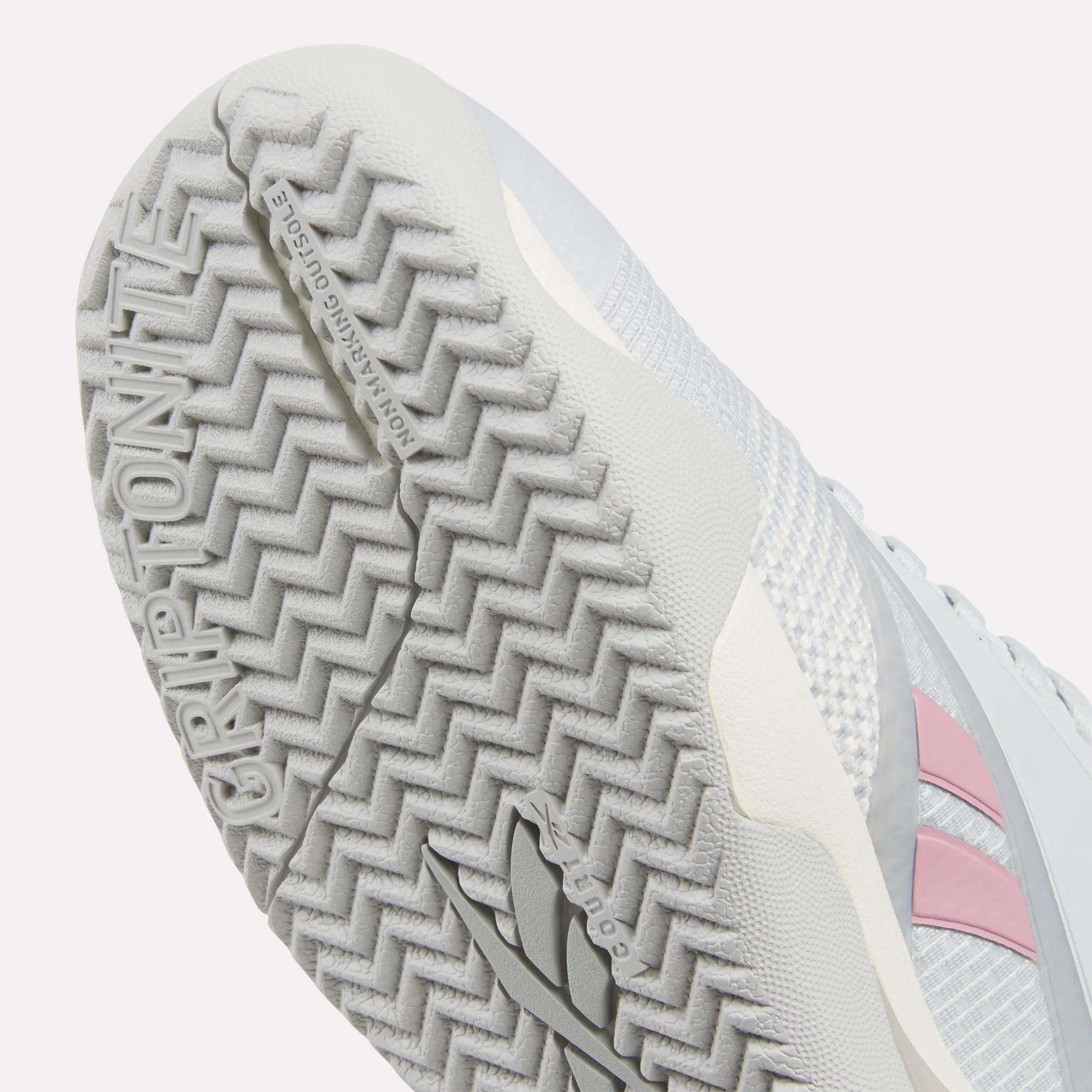 Close-up of the Women's Nano Court Training Shoes sole, showing a textured herringbone grip and GRIPTONITE embossed on the Griptonite rubber outsole with a pink Reebok logo—perfect for court sports.