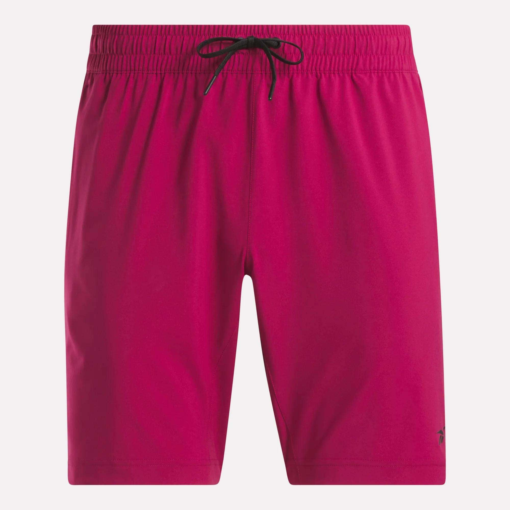 Men's Workout Ready Shorts 9" by Reebok in bright pink, with an elastic waistband and black drawstring, shown on a white background. Made from Speedwick fabric, these men's shorts feature a small logo near the left hem.