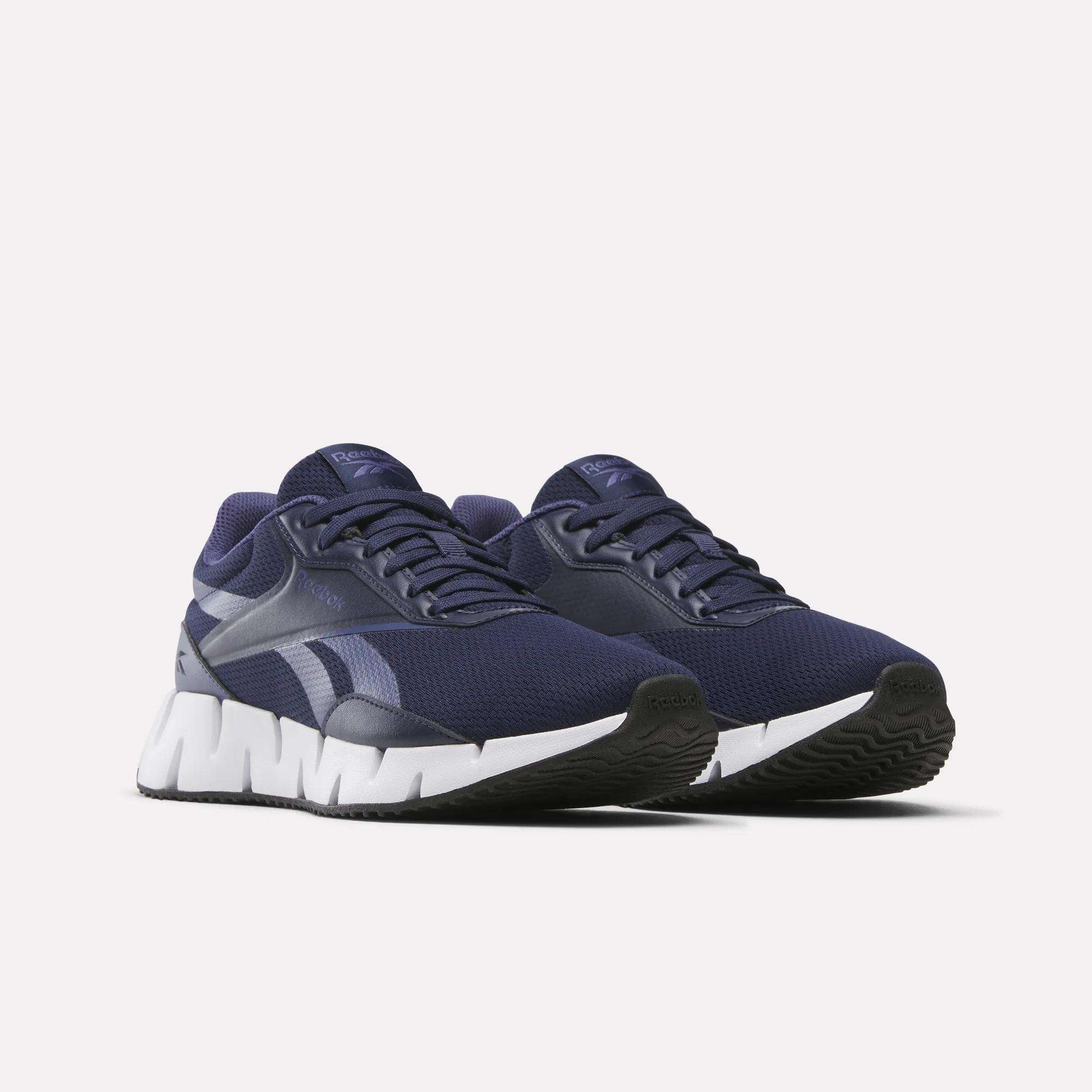 The Reebok Women's Zig Dynamica STR Shoes feature a navy blue design, white chunky soles, and silver logos, shown on a plain light background.