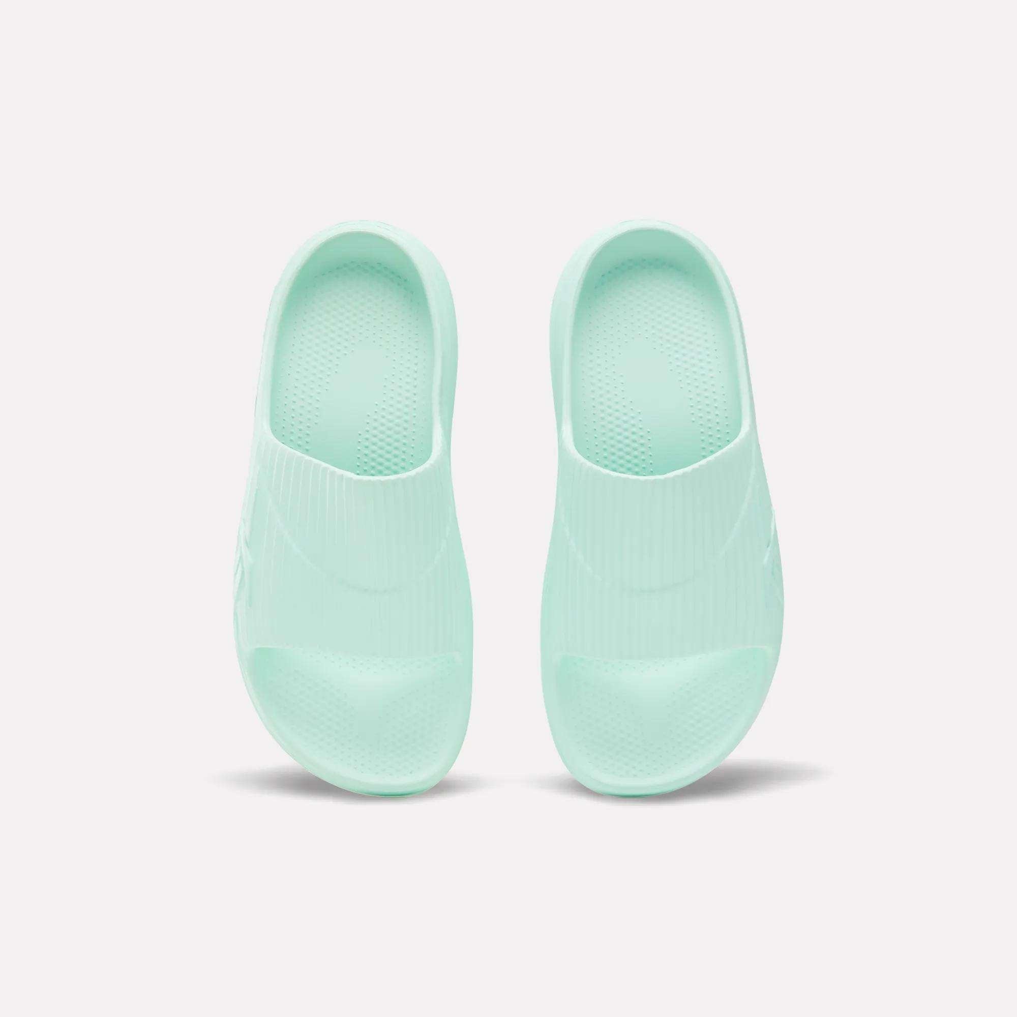 A pair of mint green Reebok DMX Recovery Walking Slides, made with super-soft foam, shown from above on a plain white background.