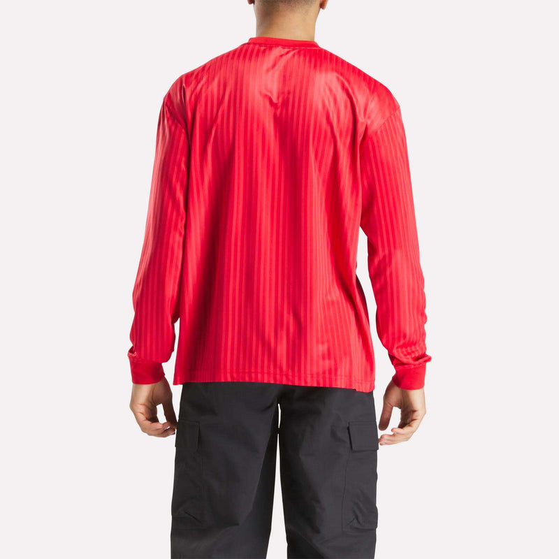 A person is seen from the back, wearing the bright red Crosscheck Long Sleeve Jersey with stripes and black cargo pants for a sporty look against a plain white background.