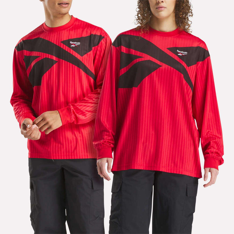 Two people wear matching Crosscheck Long Sleeve Jerseys and black pants for a coordinated sporty look. The red jacquard jerseys feature bold black geometric designs on a clean white background.