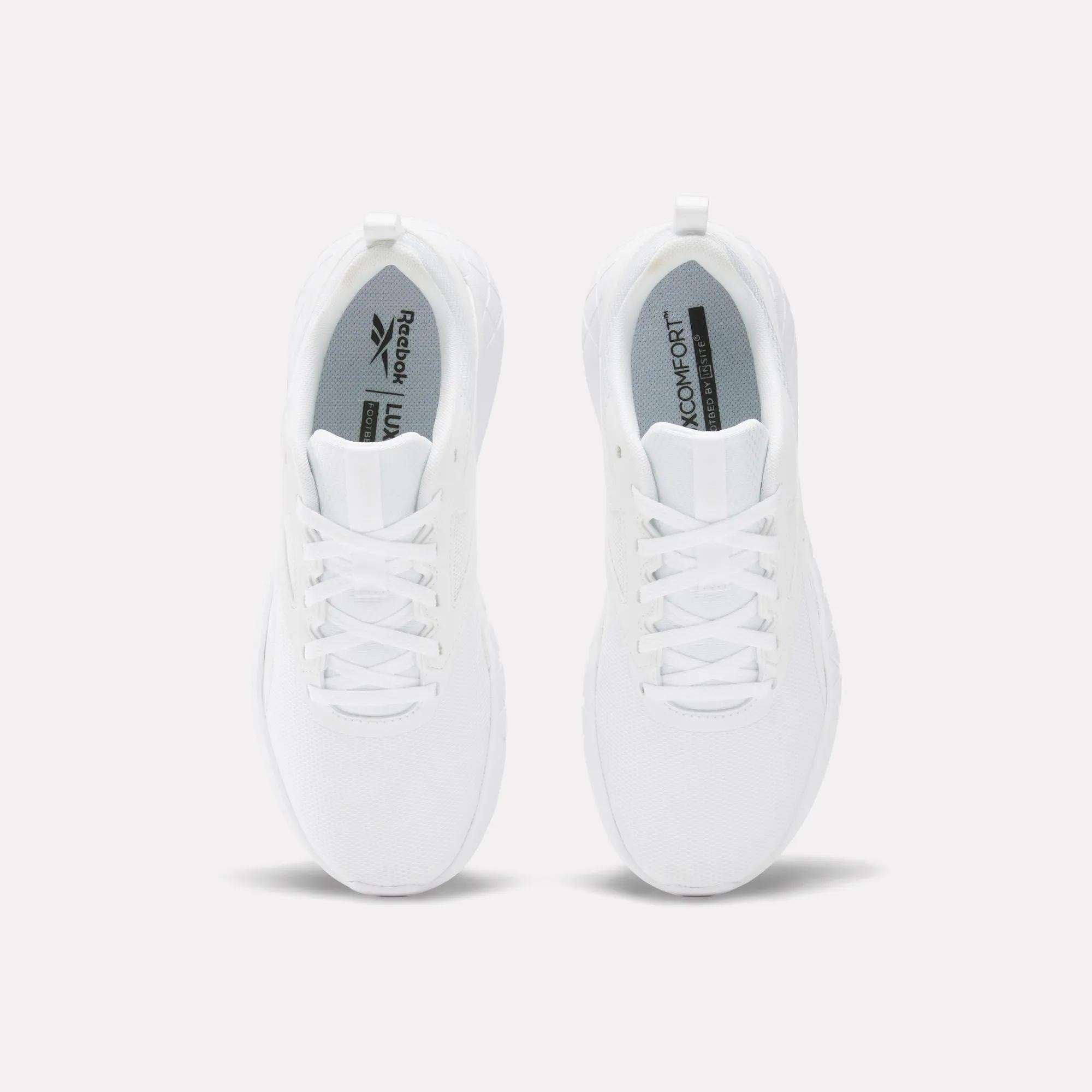 A pair of white Reebok Women's Flexagon Energy 4 Training Shoes viewed from above, displaying laces, a mesh texture, and insoles with “Reebok” and “LITE 3.0 COMFORT” in black. These lightweight shoes provide responsive cushioning.