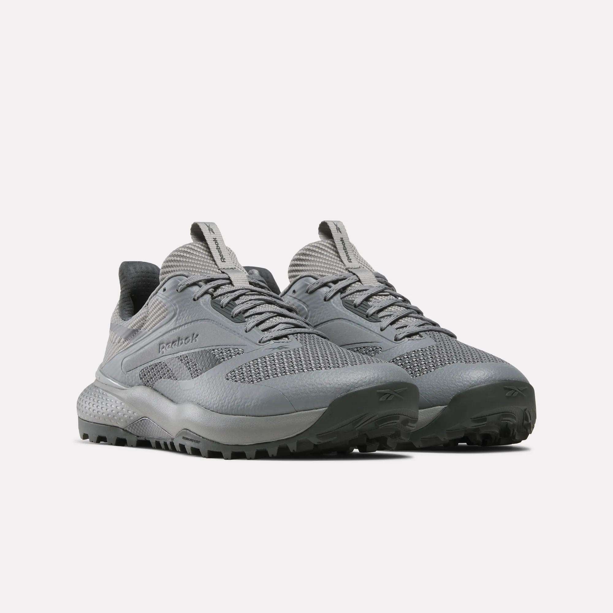 A pair of gray Reebok Nano Golf Shoes featuring textured soles, a lightweight FlexWeave upper, and tongue pull tabs, displayed against a plain white background.