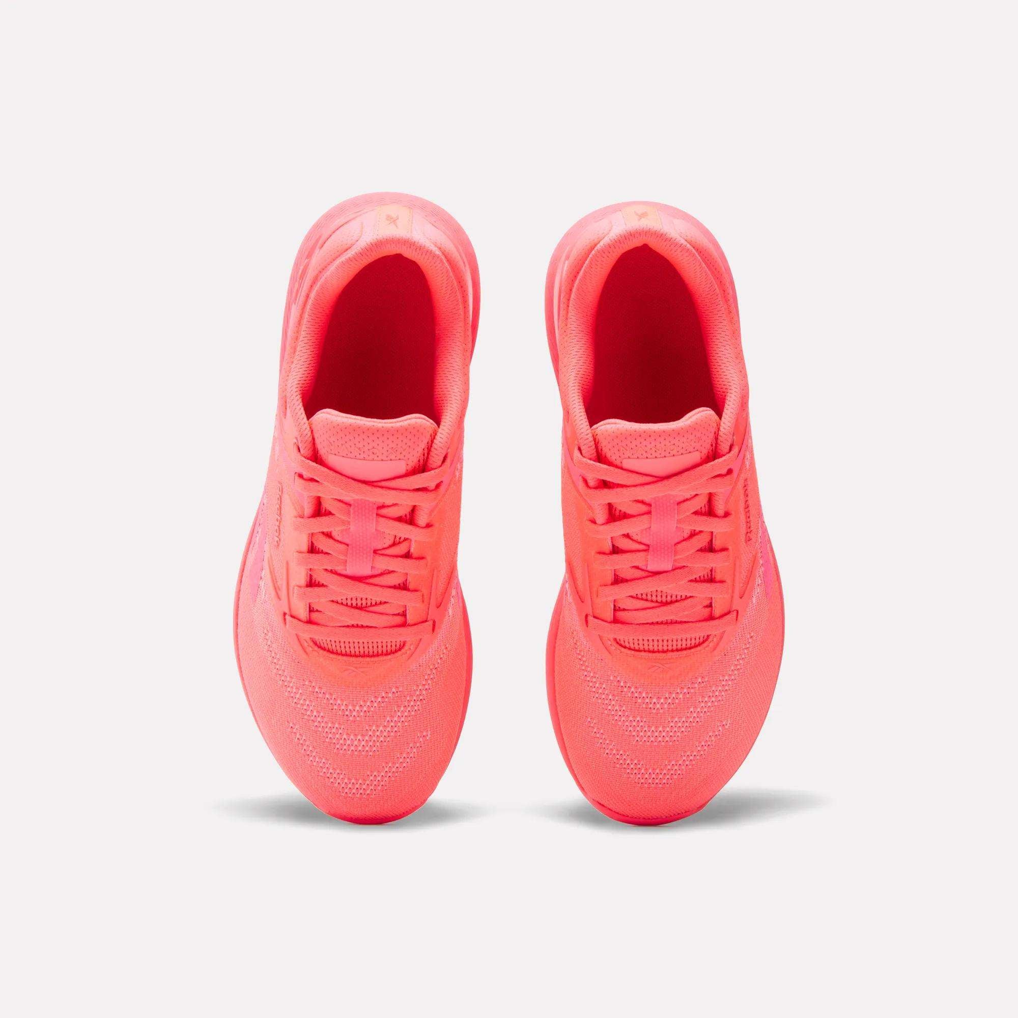 A pair of Reebok Women's Nano X5 Training Shoes in neon pink is shown from above, highlighting the tops, laces, and mesh details against a plain white background.