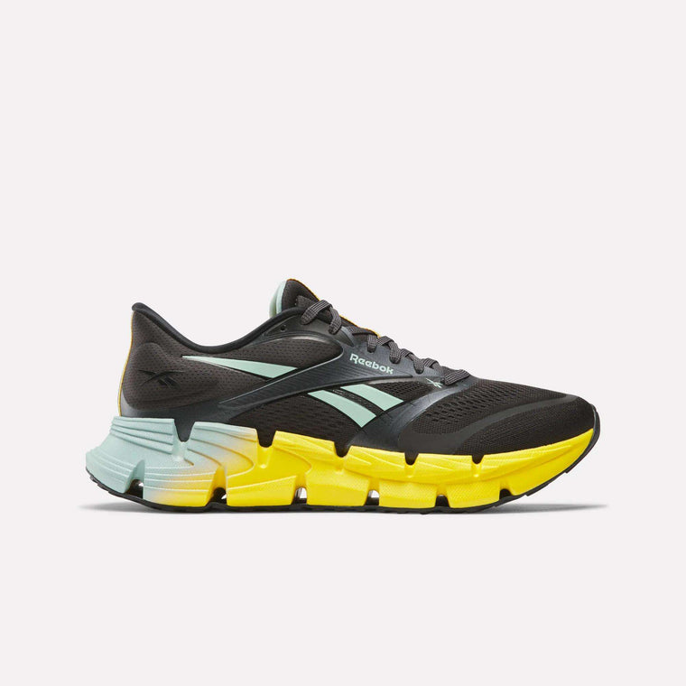 The Reebok Men's FloatZig 2 Running Shoes in black feature mint green stripes and logo, Superfloat+ cushioning, and a chunky segmented sole that fades from bright yellow at the toe to light blue at the heel, shown on a white background.