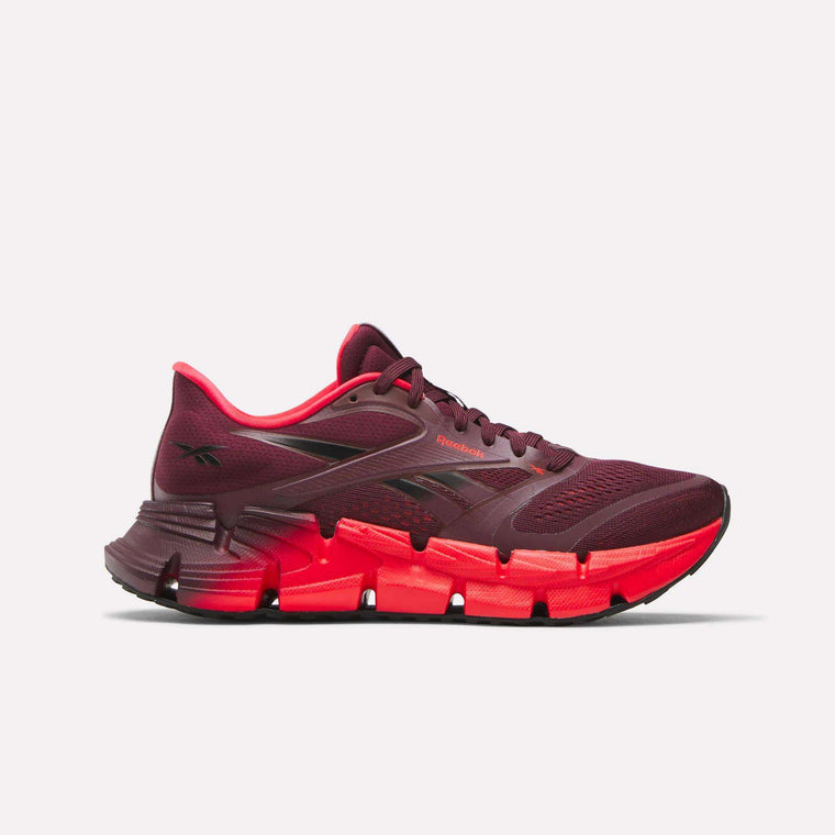 The Reebok Women's FloatZig 2 Running Shoes feature a burgundy color with black accents, mesh detailing, Superfloat+ cushioning, and a bright red sole, shown against a white background.