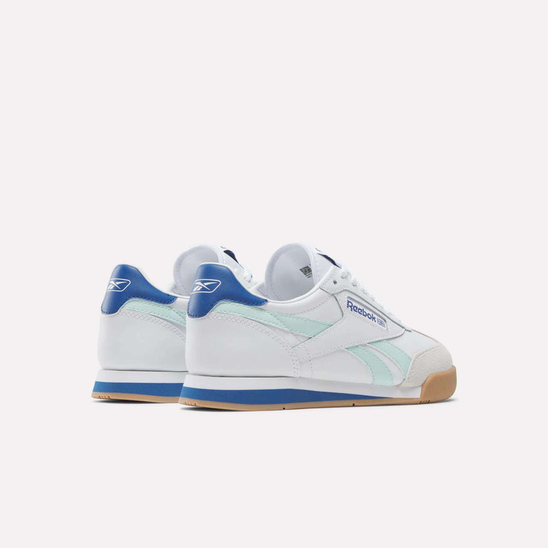 The Reebok Campio XT Shoes for Big Kids feature white uppers, light blue side stripes, blue heel tabs, gum rubber soles, and a retro soccer-inspired design with the Reebok logo on the side and heel.