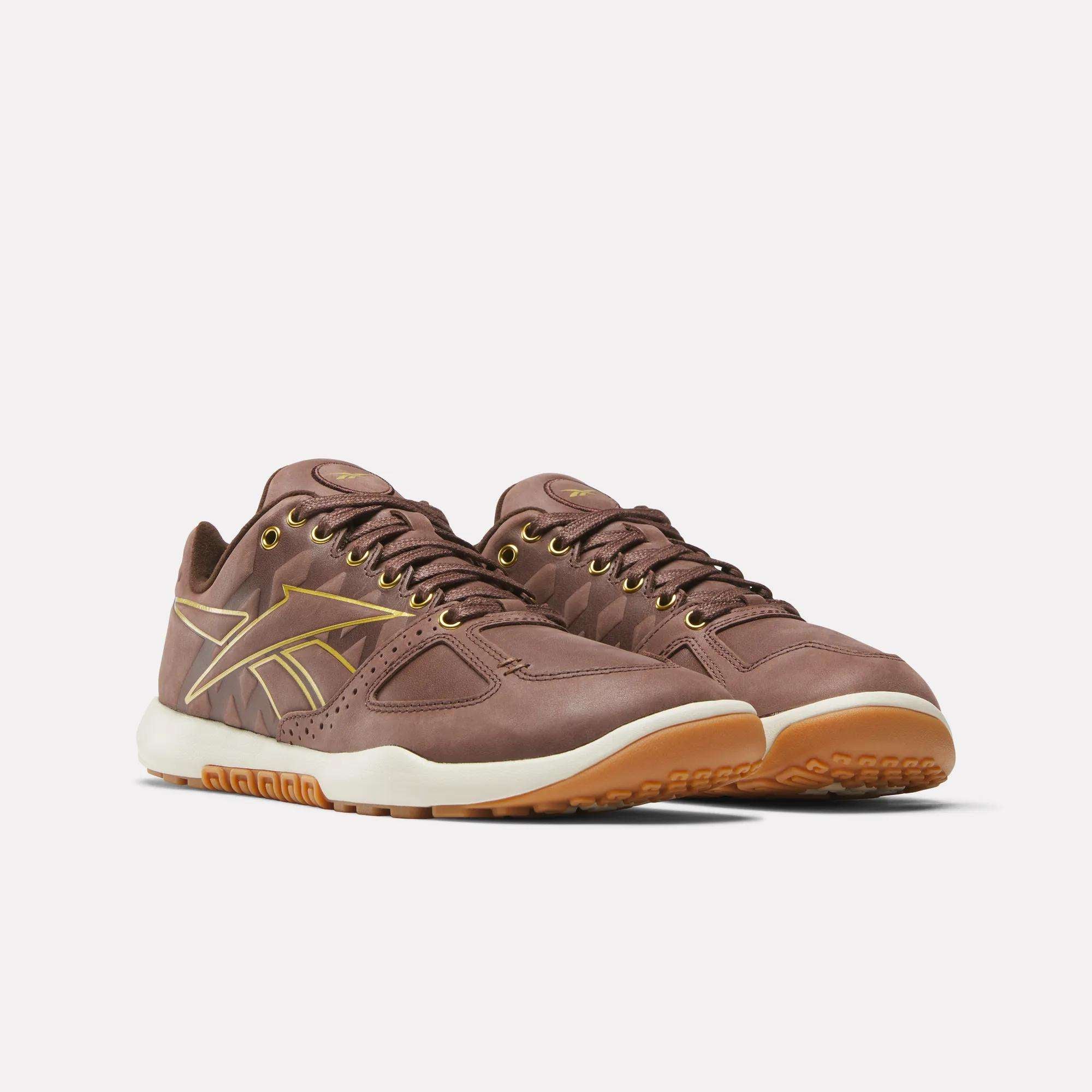 Reebok Nano 2.0 Training Shoes in brown with gold accents, pebbled leather details, white midsoles, and gum-colored outsoles are shown against a plain white background.