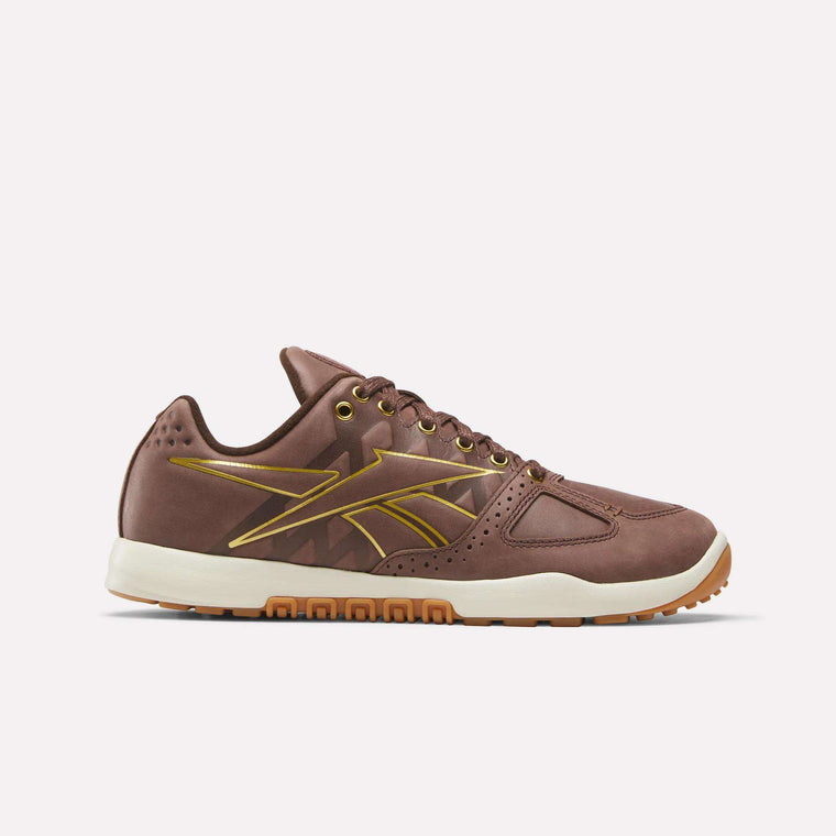 The Reebok Nano 2.0 Training Shoes in brown feature pebbled leather, gold accents, a white midsole, and a gum sole, shown in side profile on a plain light background.