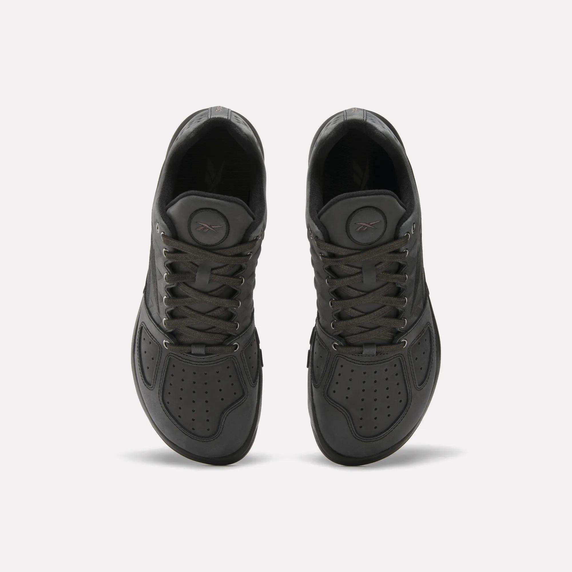 A pair of Reebok Nano 2.0 Training Shoes in black, seen from above with perforated pebbled leather toe boxes, lace-up closures, and round pump buttons on the tongues, displayed on a plain white background.