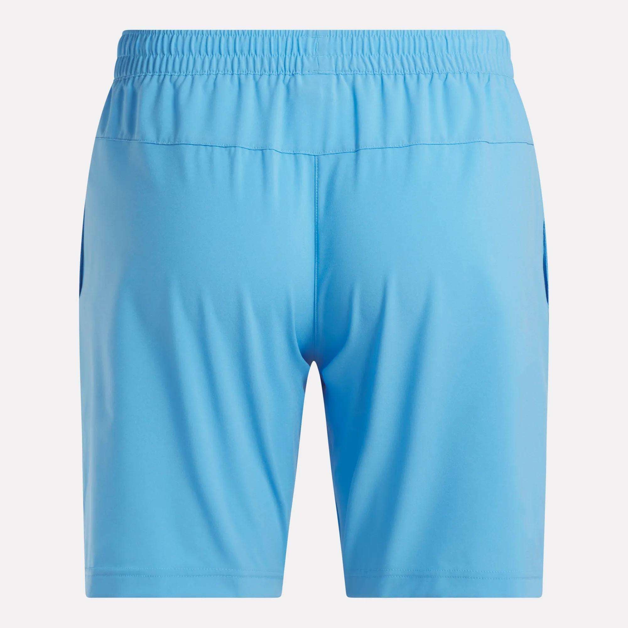 Back view of a pair of Reebok Men's Workout Ready Shorts 9" in light blue, featuring an elastic waistband and two side pockets, made from Speedwick fabric, shown on a plain white background.