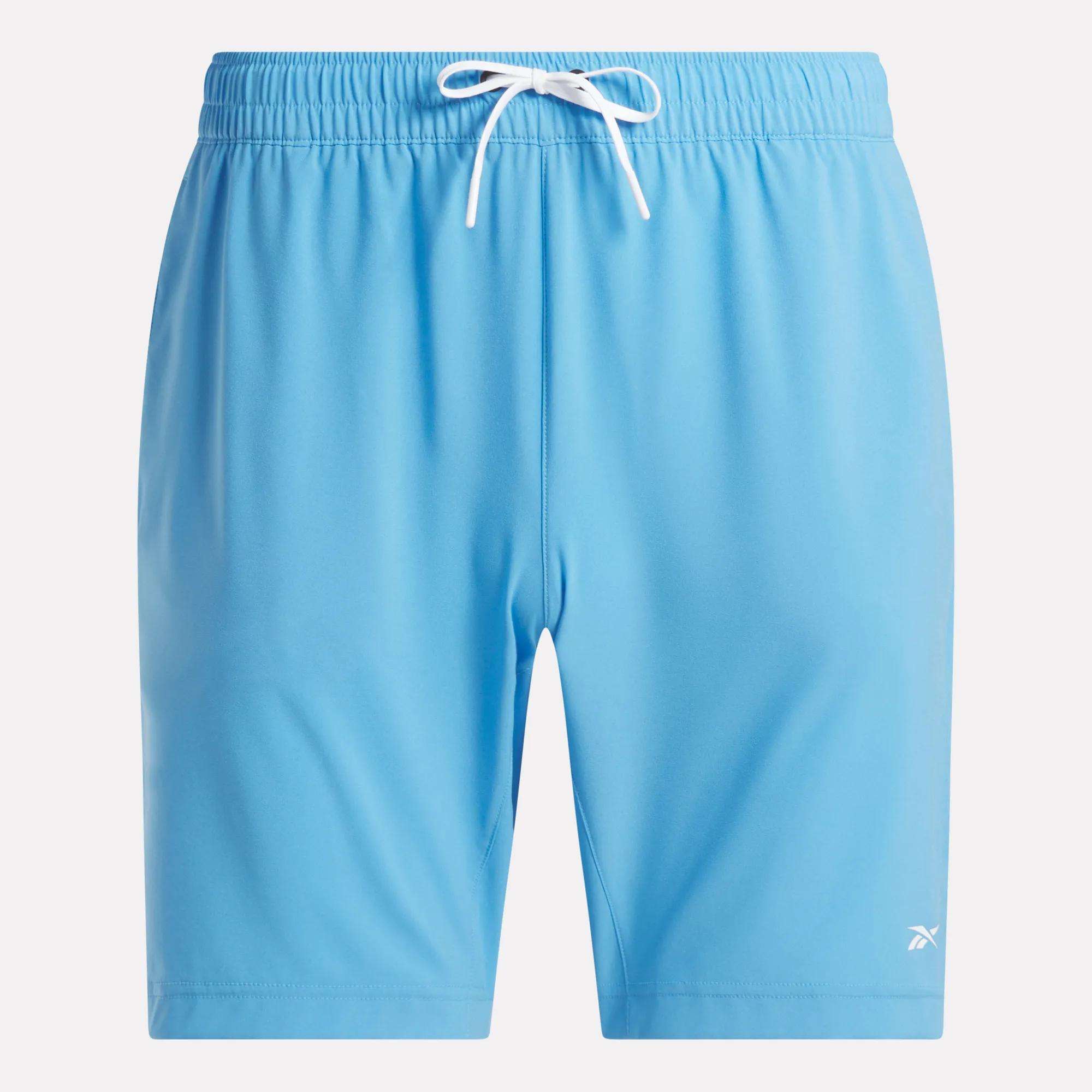 Men's Workout Ready Shorts 9" by Reebok in light blue, featuring an elastic waistband, white drawstring, and small white logo on the lower left leg. Made of Speedwick fabric for comfort during workouts. Displayed on a white background.