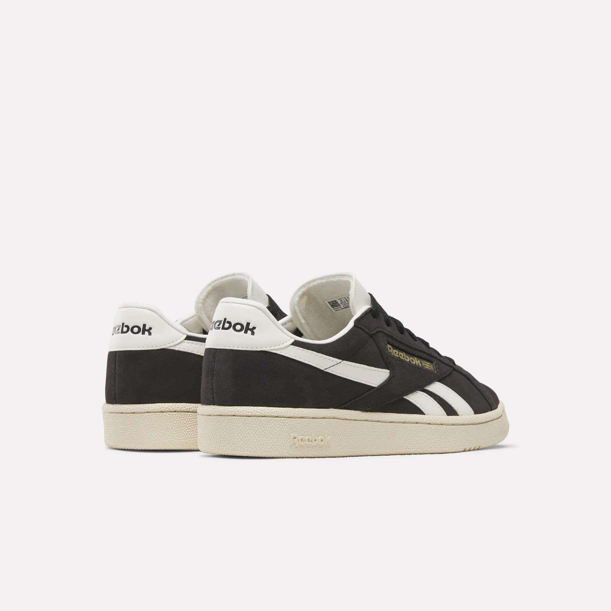 The Reebok Club C Ground UK Shoes feature a black suede upper, white soles, white stripes, and white heel panels, displayed from the back and side against a plain light background.