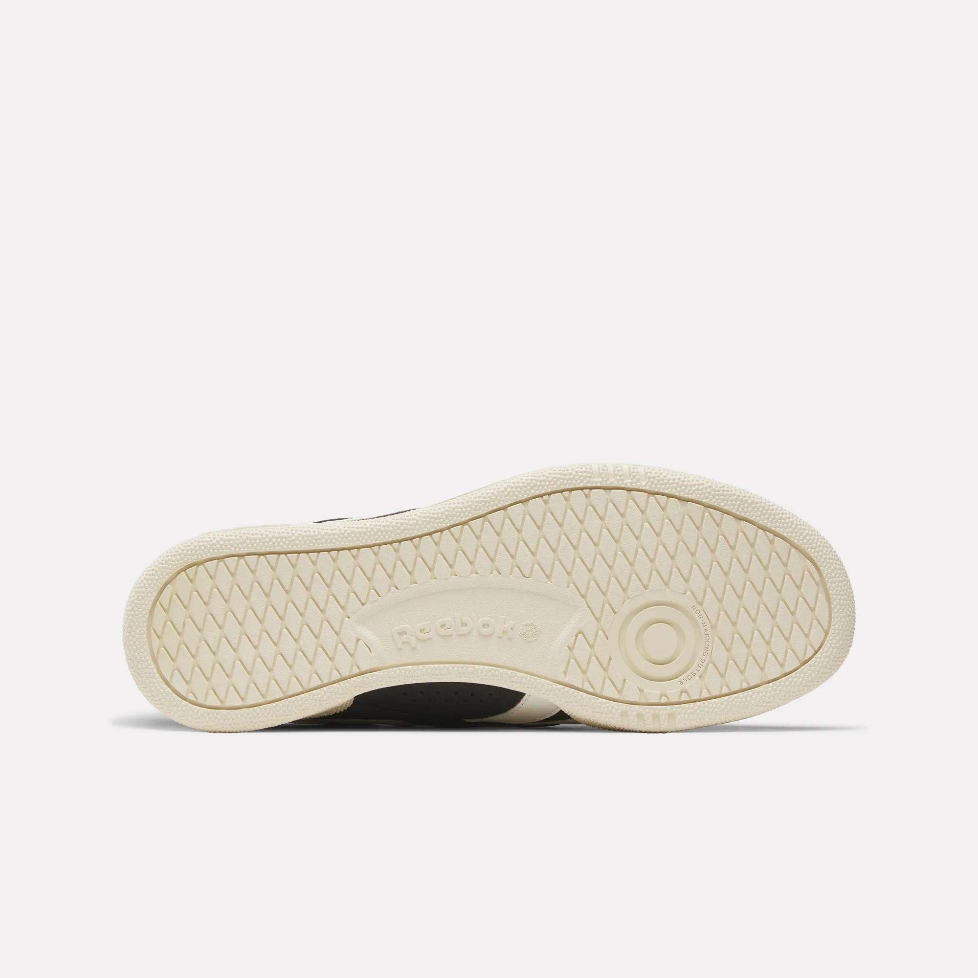The image shows the outsole of Reebok Club C Ground UK Shoes, featuring a light beige rubber sole with herringbone tread patterns, circular accents, and embossed Reebok branding.