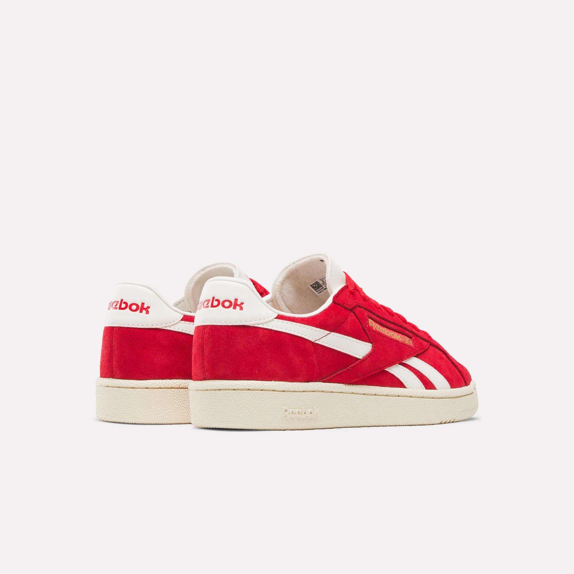 The Reebok Club C Ground UK Shoes are red suede sneakers with white stripes and soles, plus metallic gold branding. The Reebok logo appears on the heel and side, all set against a plain light background.