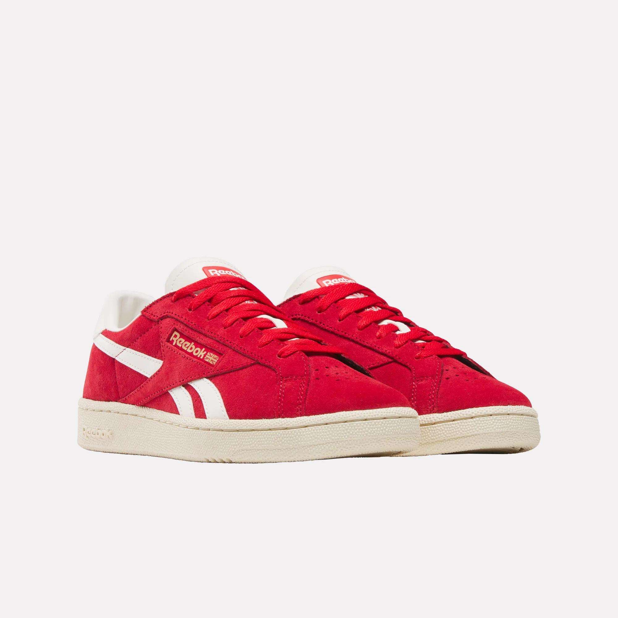 A pair of Reebok Club C Ground UK Shoes featuring a red suede upper, white accents and soles, plus the Reebok logo on the side and tongue, displayed against a plain white background.
