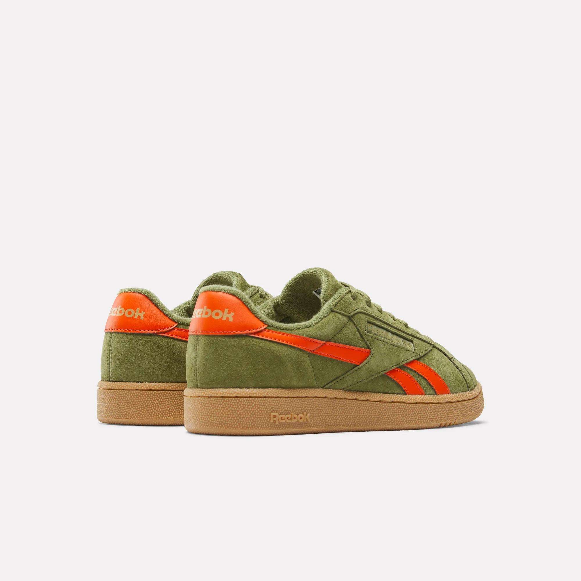 The Reebok Club C Grounds UK Shoes are green and orange suede sneakers inspired by Reebok heritage.