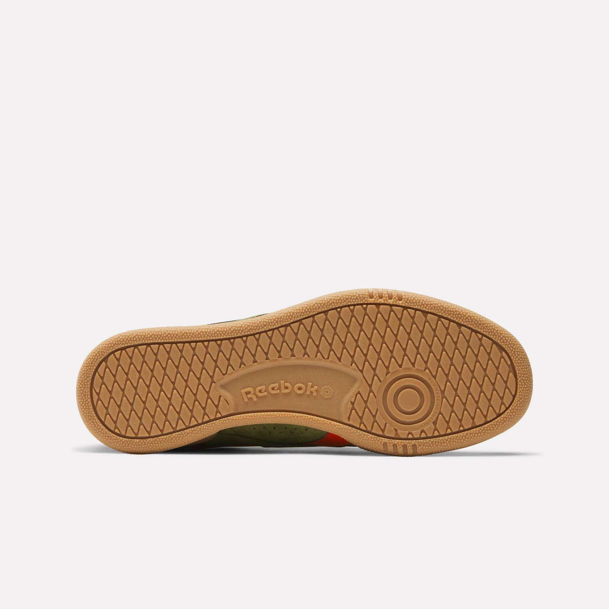 The image shows the sole of the Reebok Club C Grounds UK Shoes, featuring a light brown color, circular heel pattern, textured grip, and a central Reebok logo, all against a plain white background.