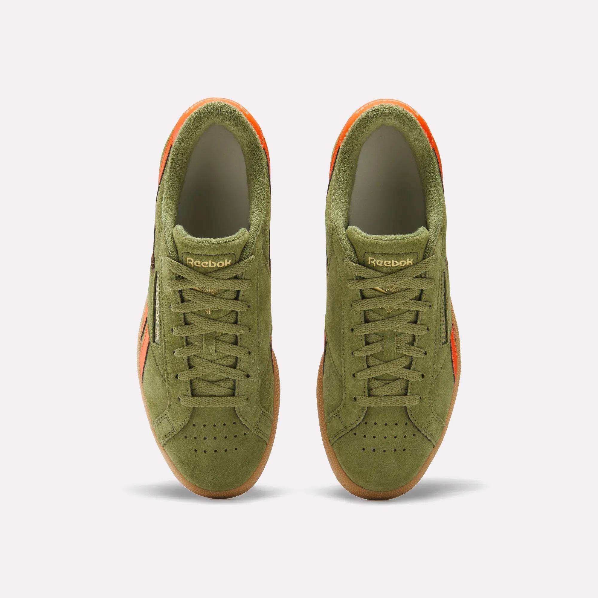 Top view of olive green Reebok Club C Grounds UK Shoes featuring orange accents, a perforated toe box, and classic Reebok branding on the tongue—nostalgic sneakers inspired by timeless style.