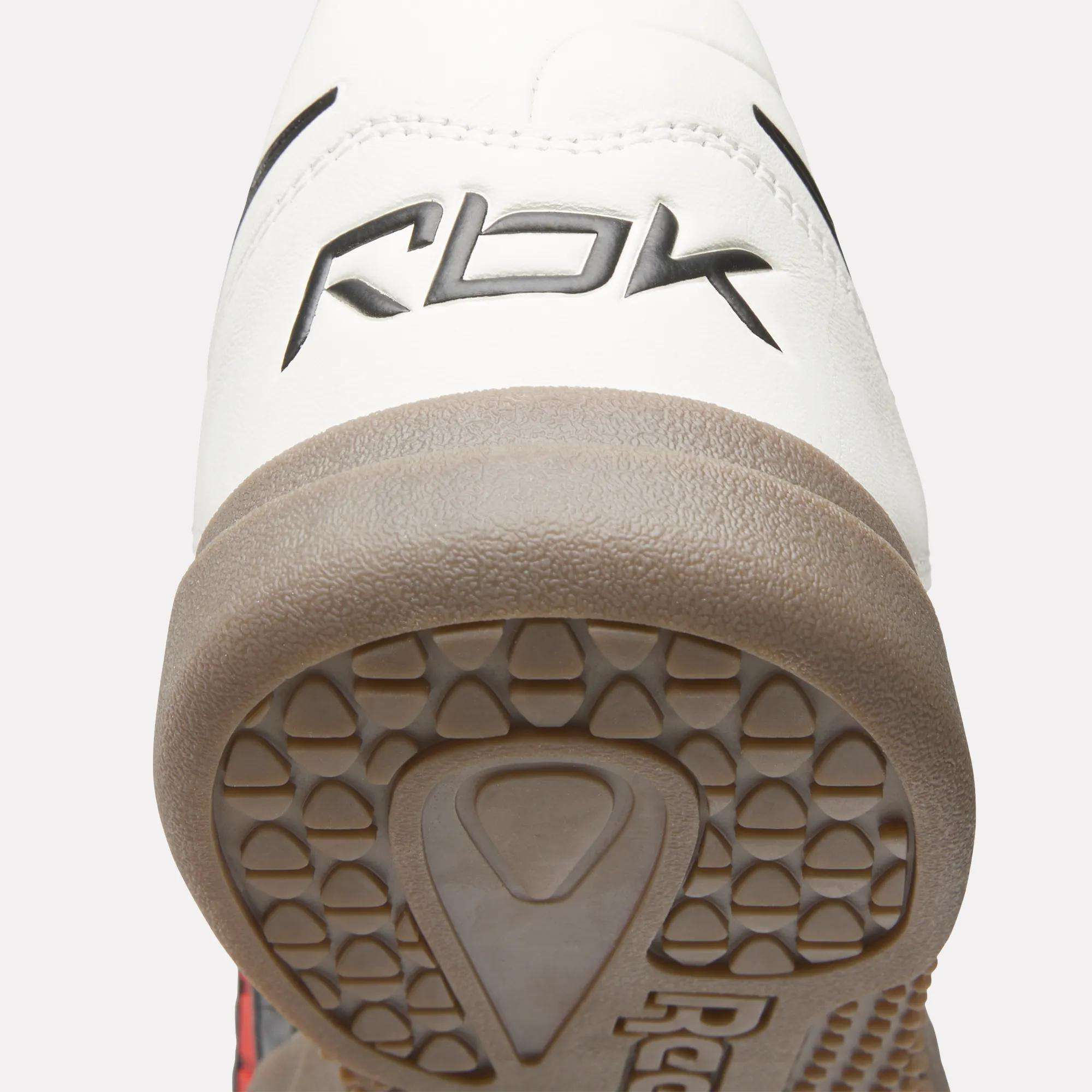 Close-up of the heel of Reebok Hammer Valde Shoes with a white leather upper, RBK branding on the back, and a textured light brown rubber outsole.