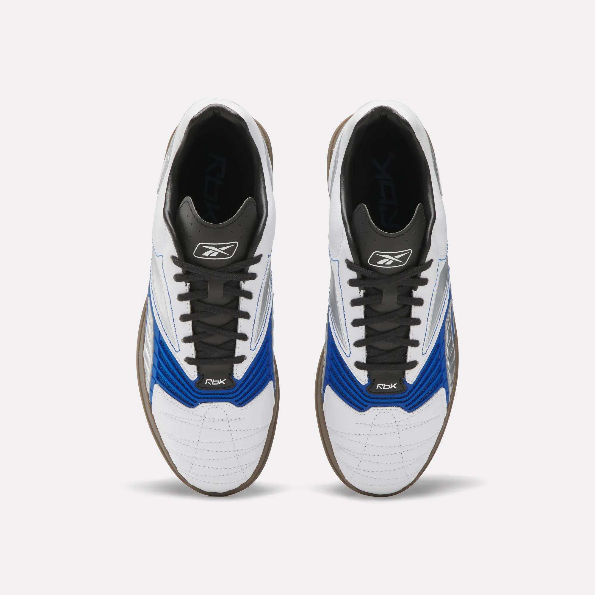 A pair of Reebok Hammer Valde Shoes seen from above, with a white leather upper, blue and black accents, black laces, brown soles, and branding on the tongue and side.