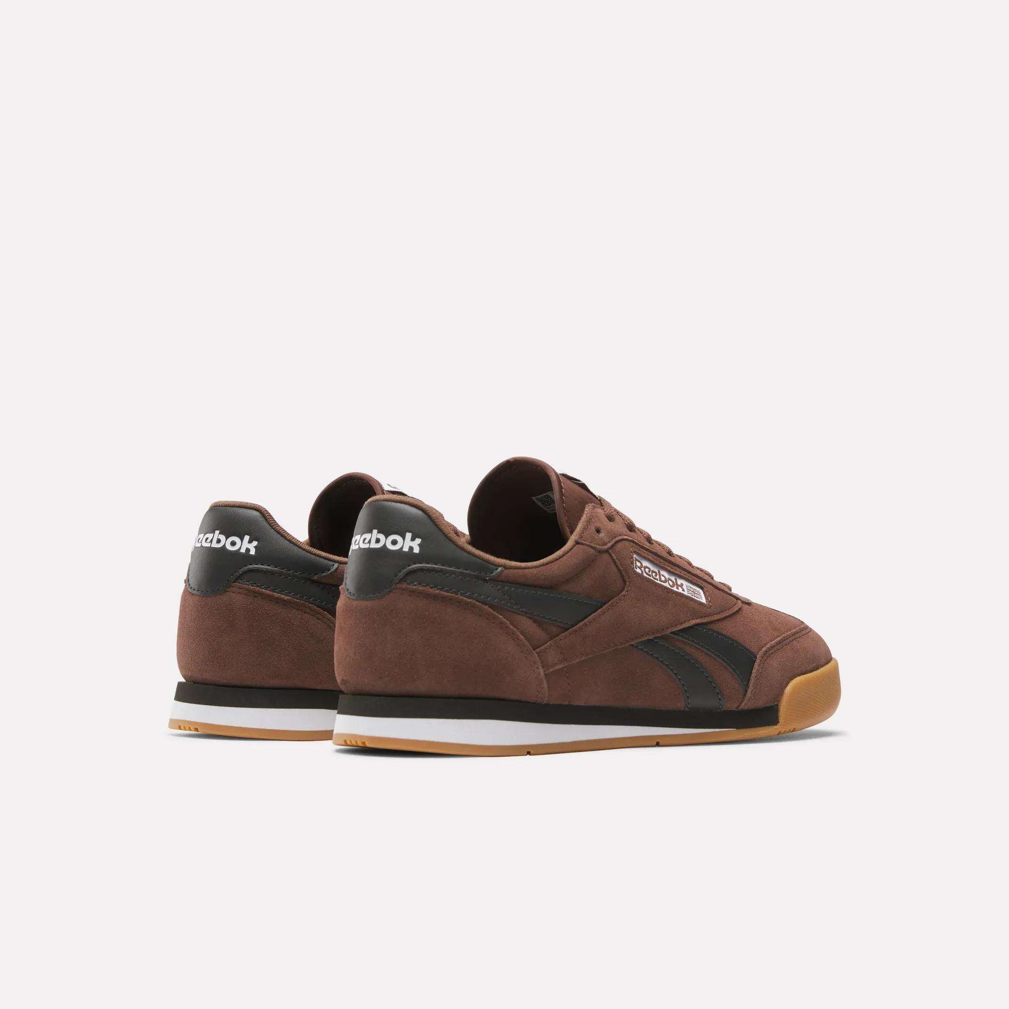 A pair of brown Reebok Campio XT Shoes with black details, white Reebok logos on the heel tabs, black side stripes, and gum rubber soles, inspired by '90s soccer style and set against a plain white background.