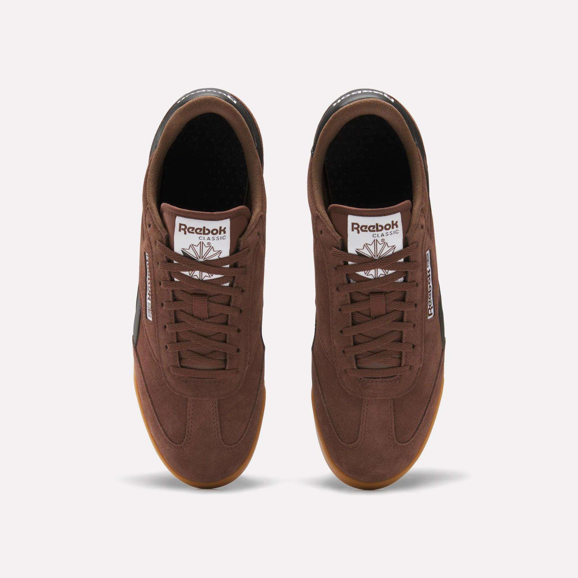 Top view of a pair of brown Reebok Campio XT Shoes with gum soles, brown laces, and white logos on the tongues and sides, inspired by '90s soccer style, shown on a plain white background.