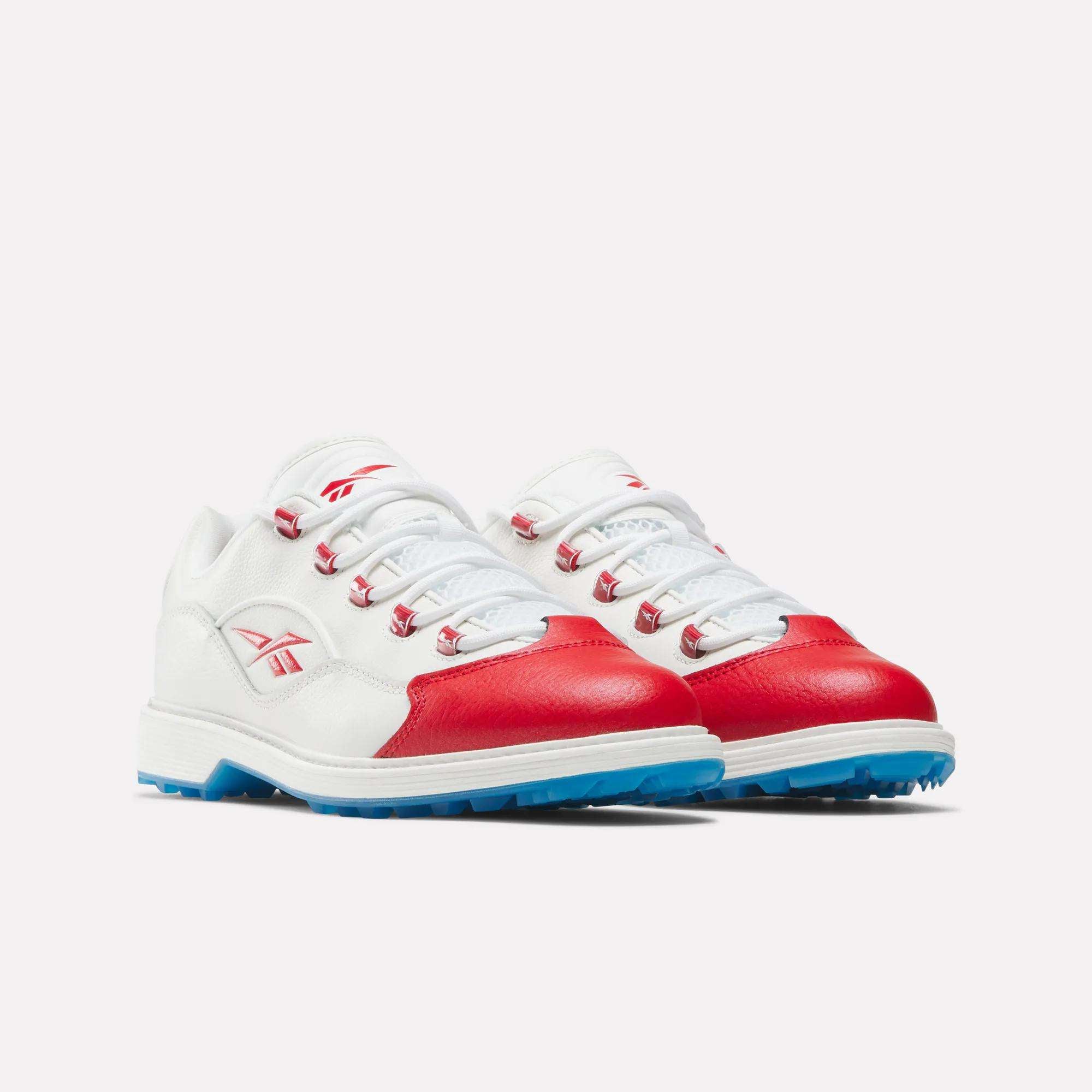 The Reebok Question Golf Shoes feature white leather with red accents on the toe and sides, blue rubber soles, and white laces, shown against a plain light background.