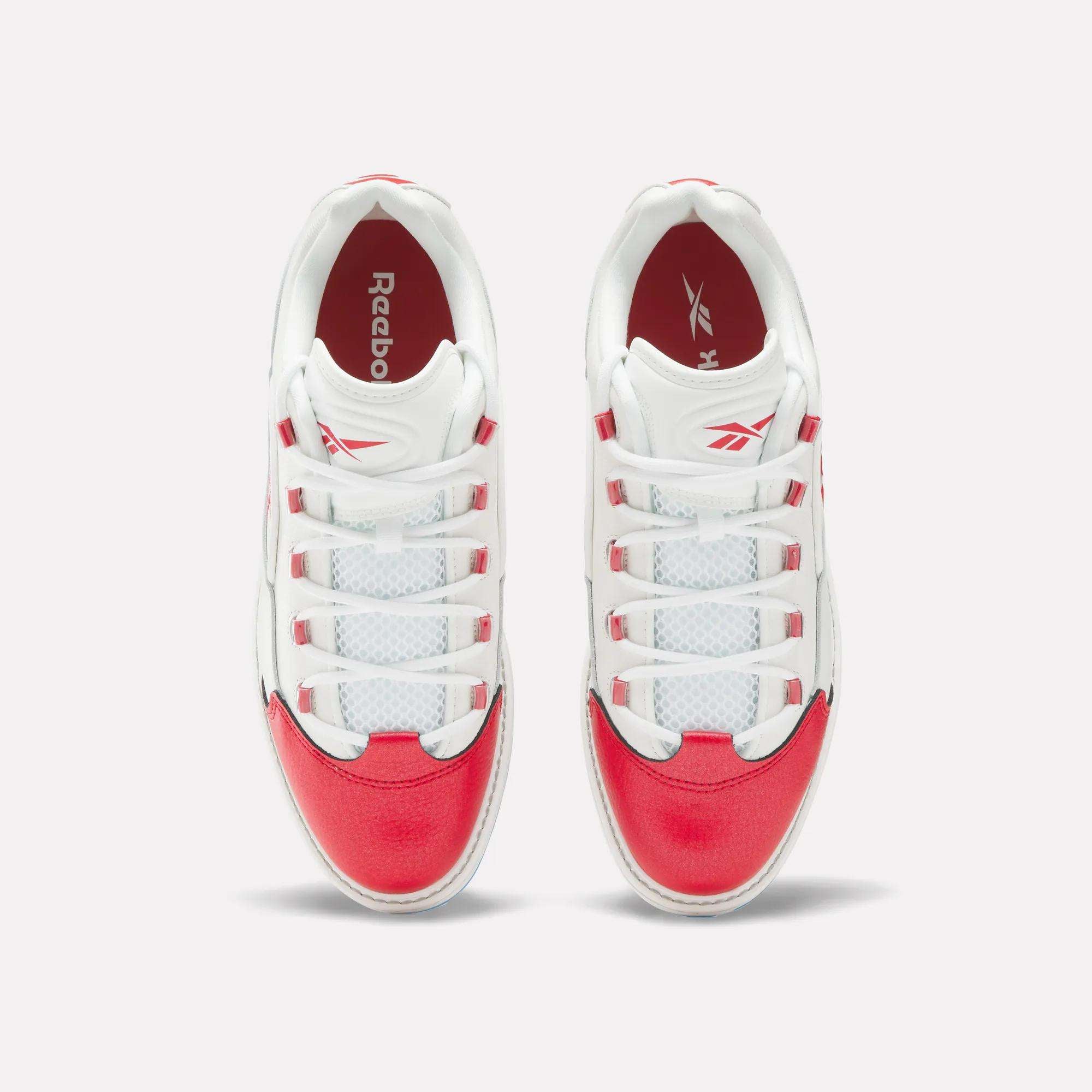 A pair of Reebok Question Golf Shoes viewed from above, showcasing white uppers with bright red accents on the toe, heel, and sides—these stylish spikeless shoes feature white laces threaded through red and white eyelets.