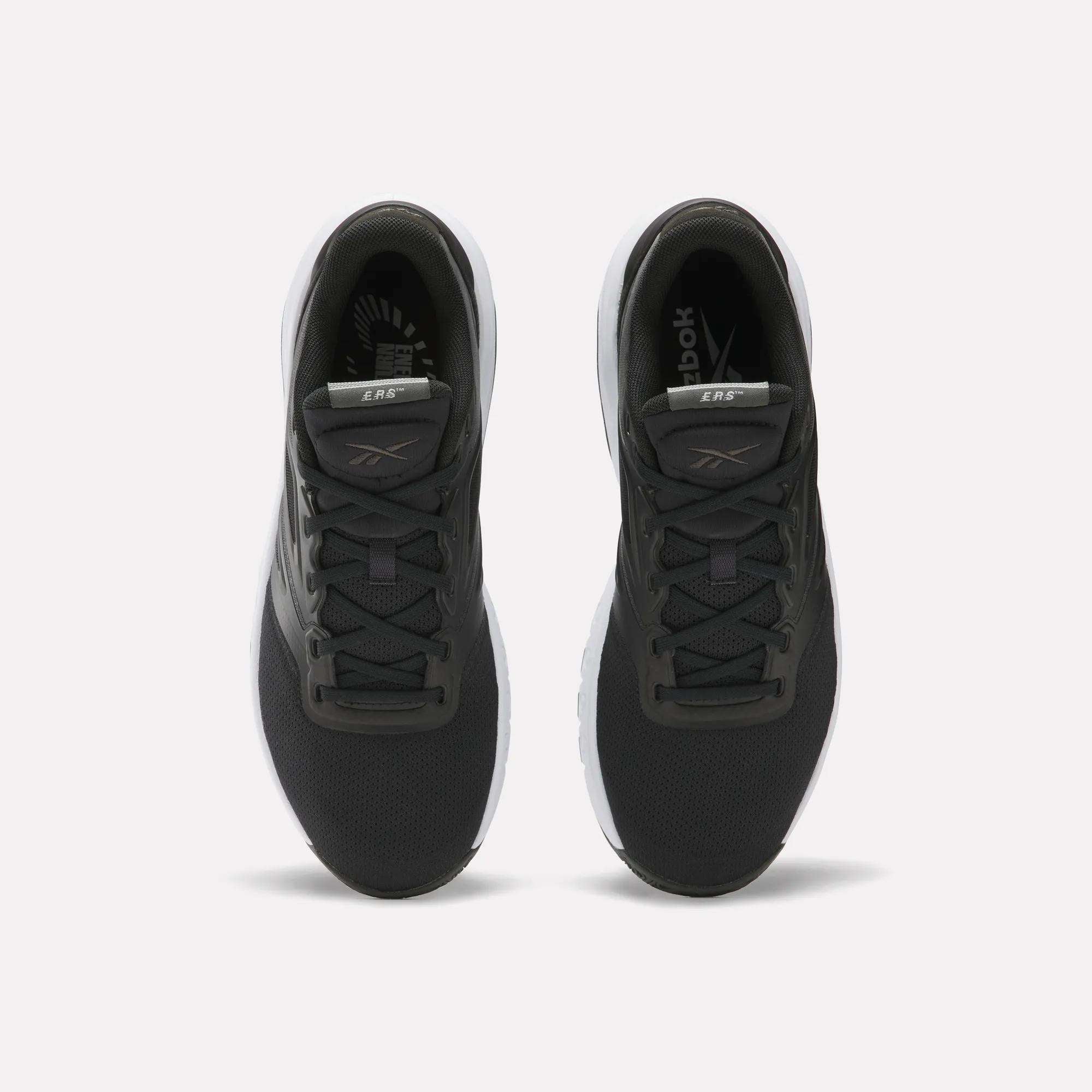 A pair of Reebok Men's ERS Training Shoes with black uppers, white soles, and gray accents on the tongue and sides are shown side by side on a plain white background, offering premium cushioning for comfort.