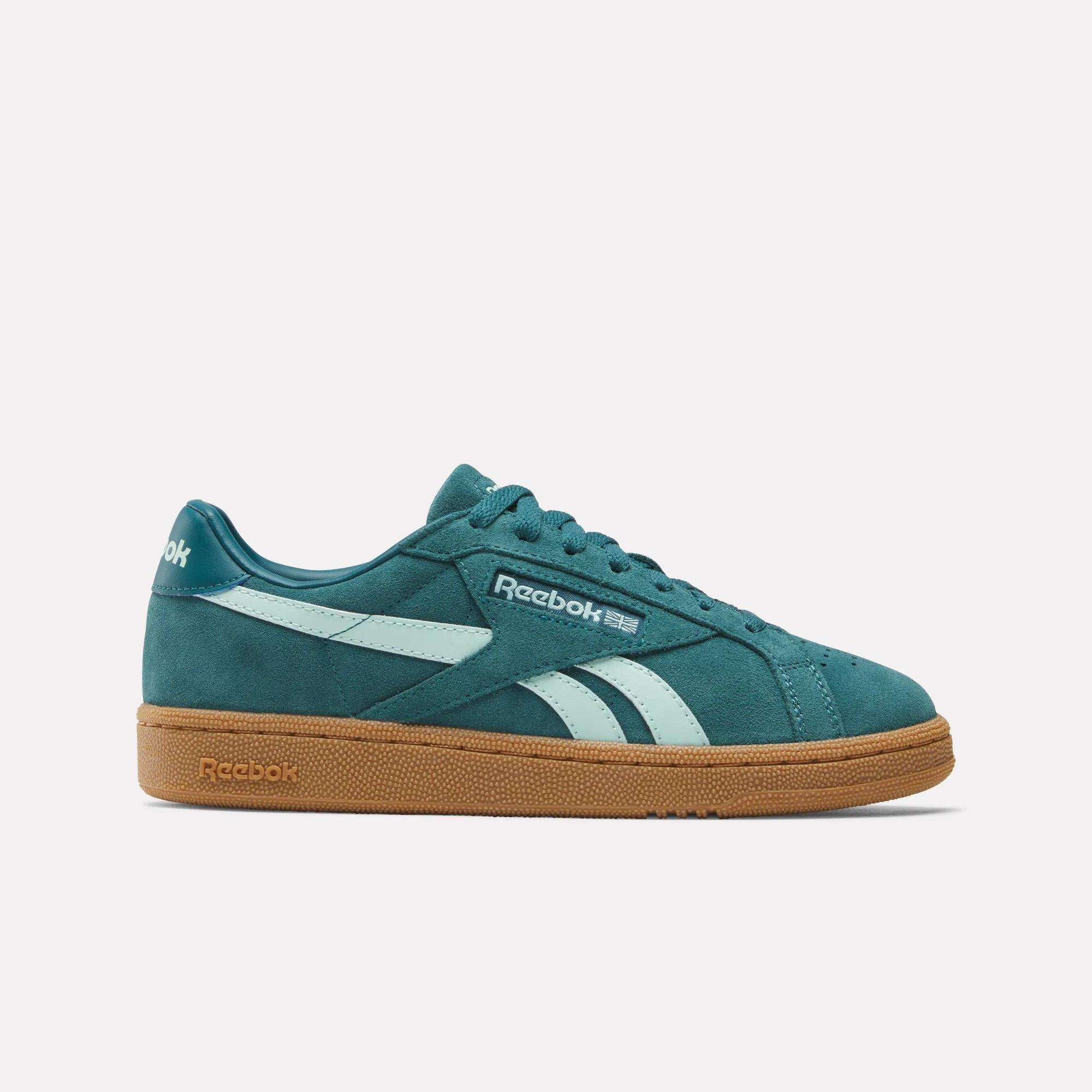 The Women's Club C Grounds UK Shoes by Reebok feature a turquoise suede upper, white stripes and logo, teal laces, and a brown rubber sole. They're showcased against a simple white background.