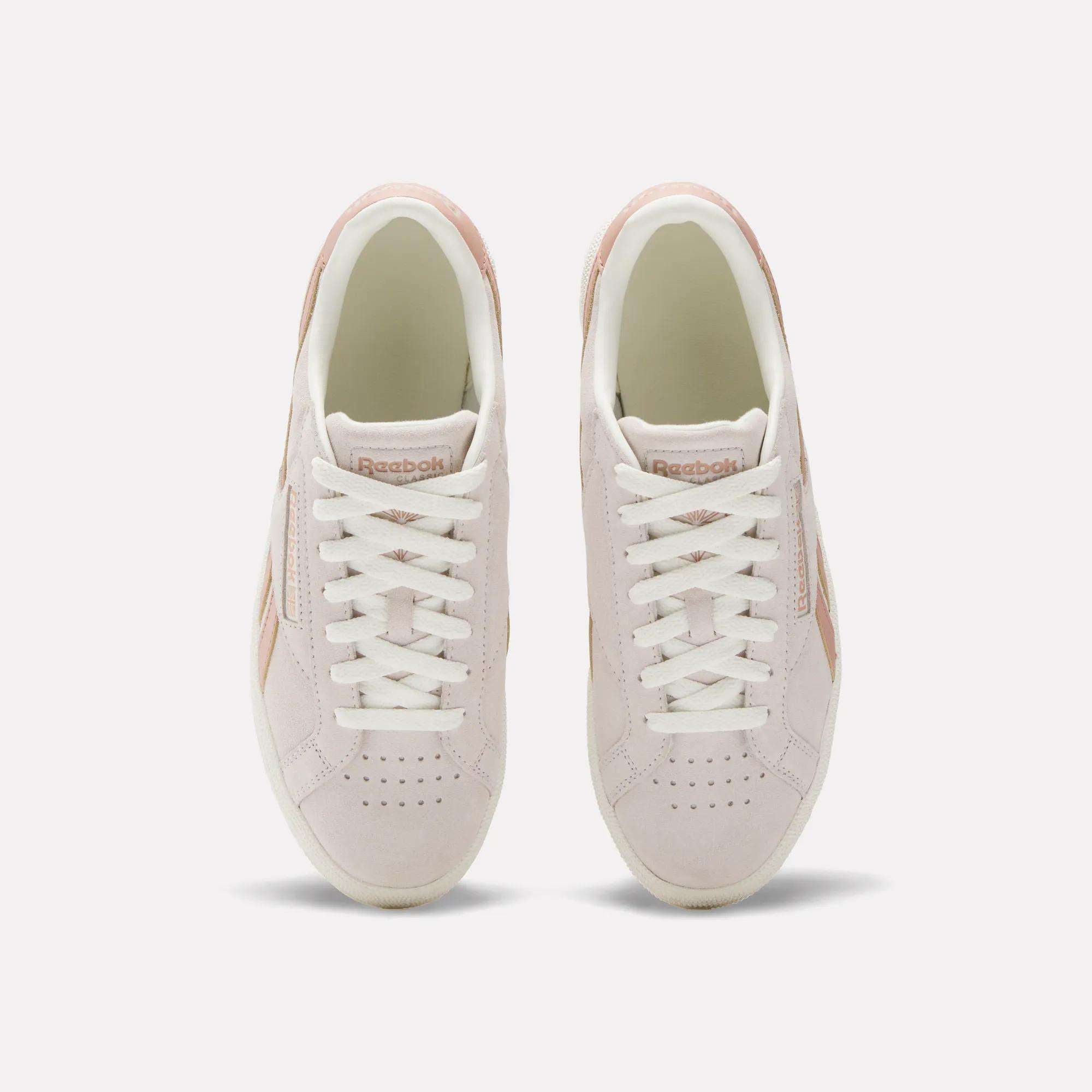 A top view of the Reebok Women's Club C Grounds UK Shoes in light pink, featuring white laces, beige details, suede and leather accents, and the Reebok logo on the tongue.