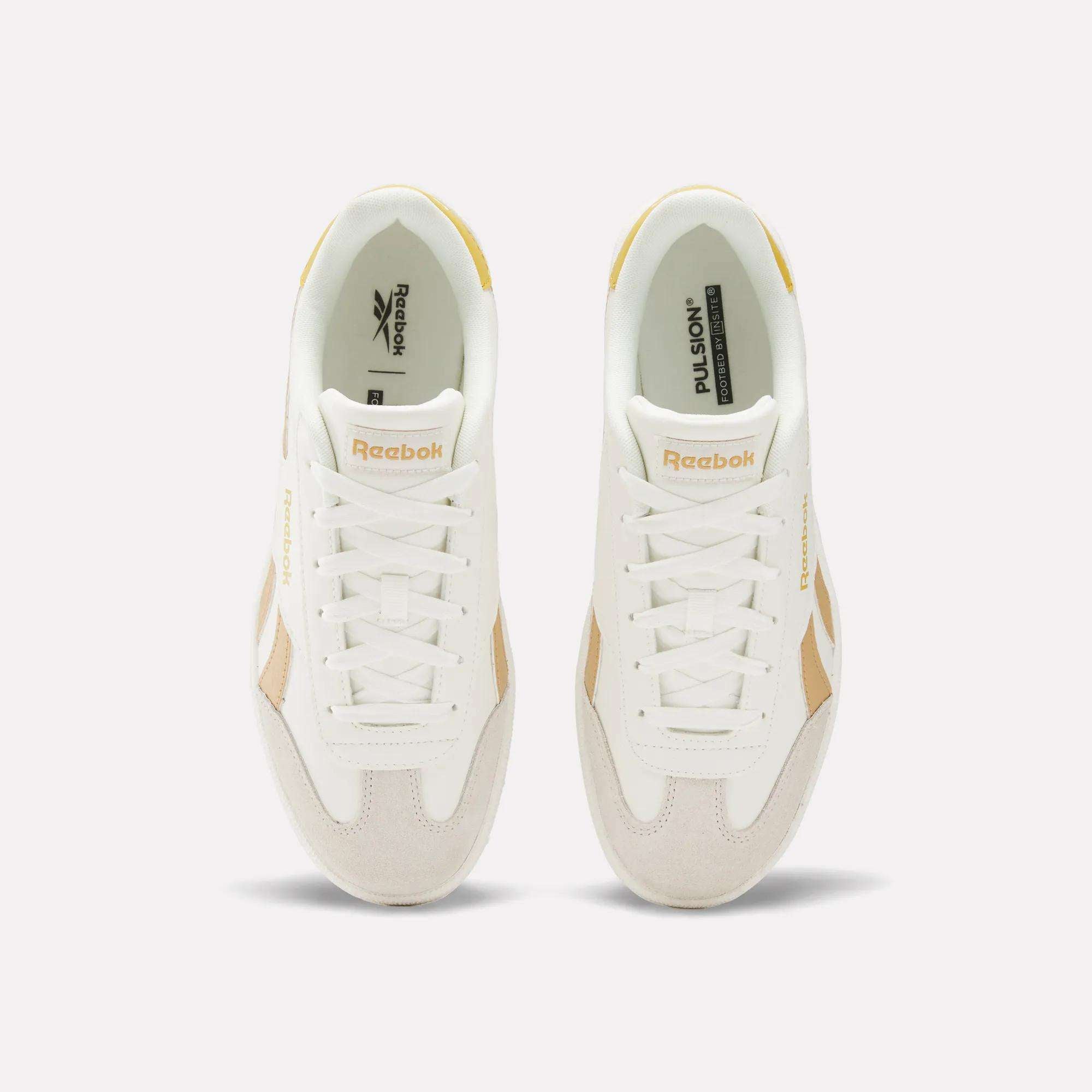 Top view of Reebok Smash Edge Shoes in white with beige details, displaying the Reebok logo on tongue and side, set against a plain light background. Ideal for those seeking stylish and comfortable indoor soccer footwear.
