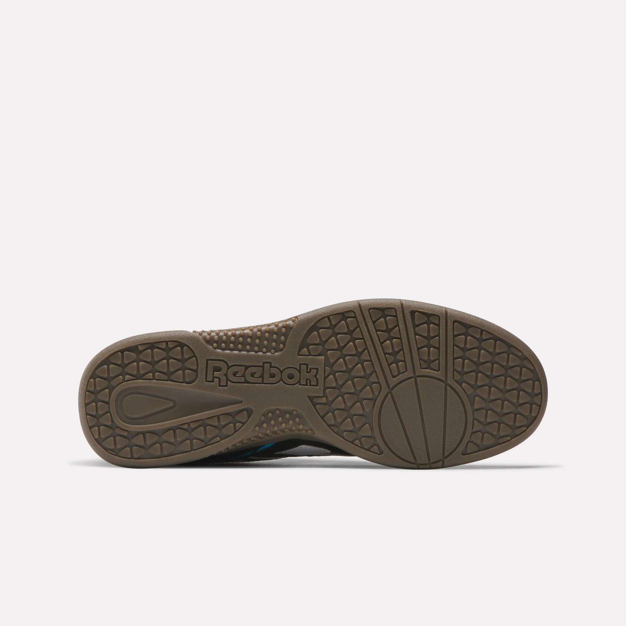 The image displays the sole of a Reebok Hammer Street Shoe in brown, featuring textured tread and a molded logo at the center. The soccer-inspired shoe is shown flat, with its sole facing upward on a plain white background.
