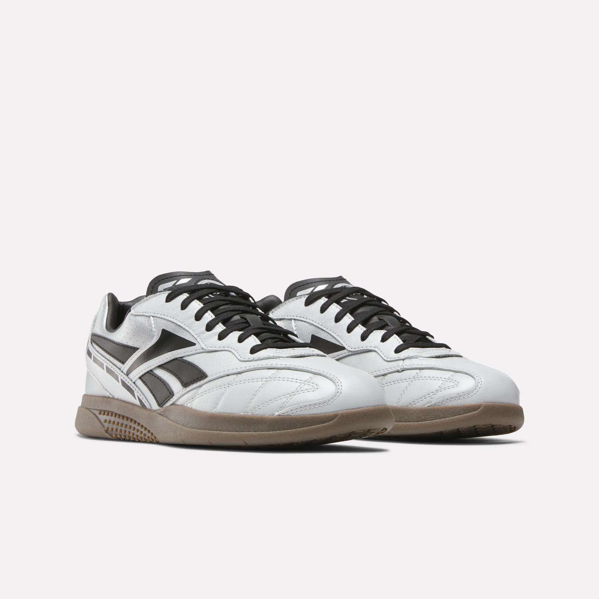 A pair of Reebok Hammer Street Shoes in white and black full-grain leather with gum soles, low-cut design, and side stripe detail, shown on a plain light background.