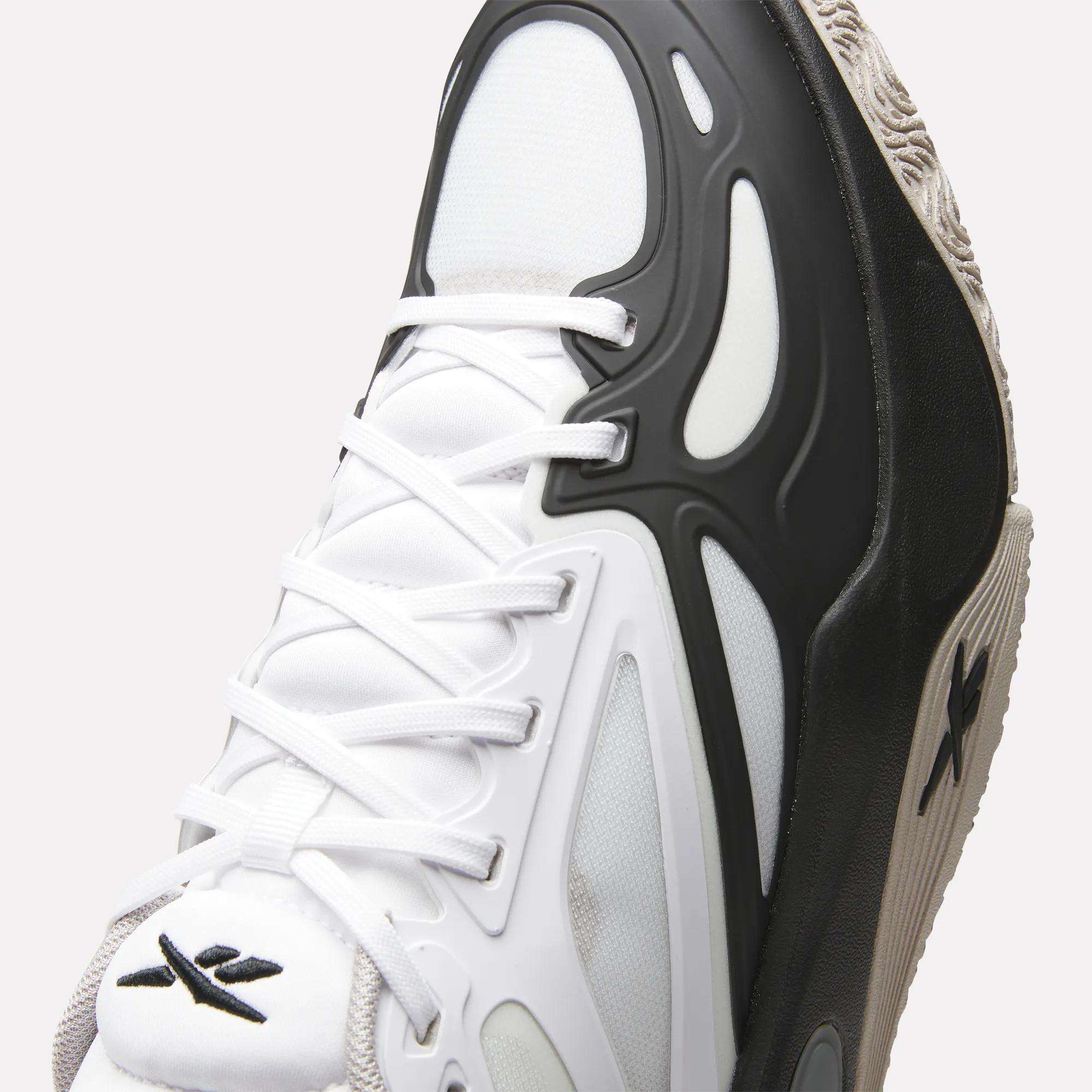 Close-up of the Reebok Engine A Basketball Shoes featuring a white mesh upper, black and white overlays, white laces, textured sole with SuperFloat foam, and a black X logo on the tongue and side for standout style.