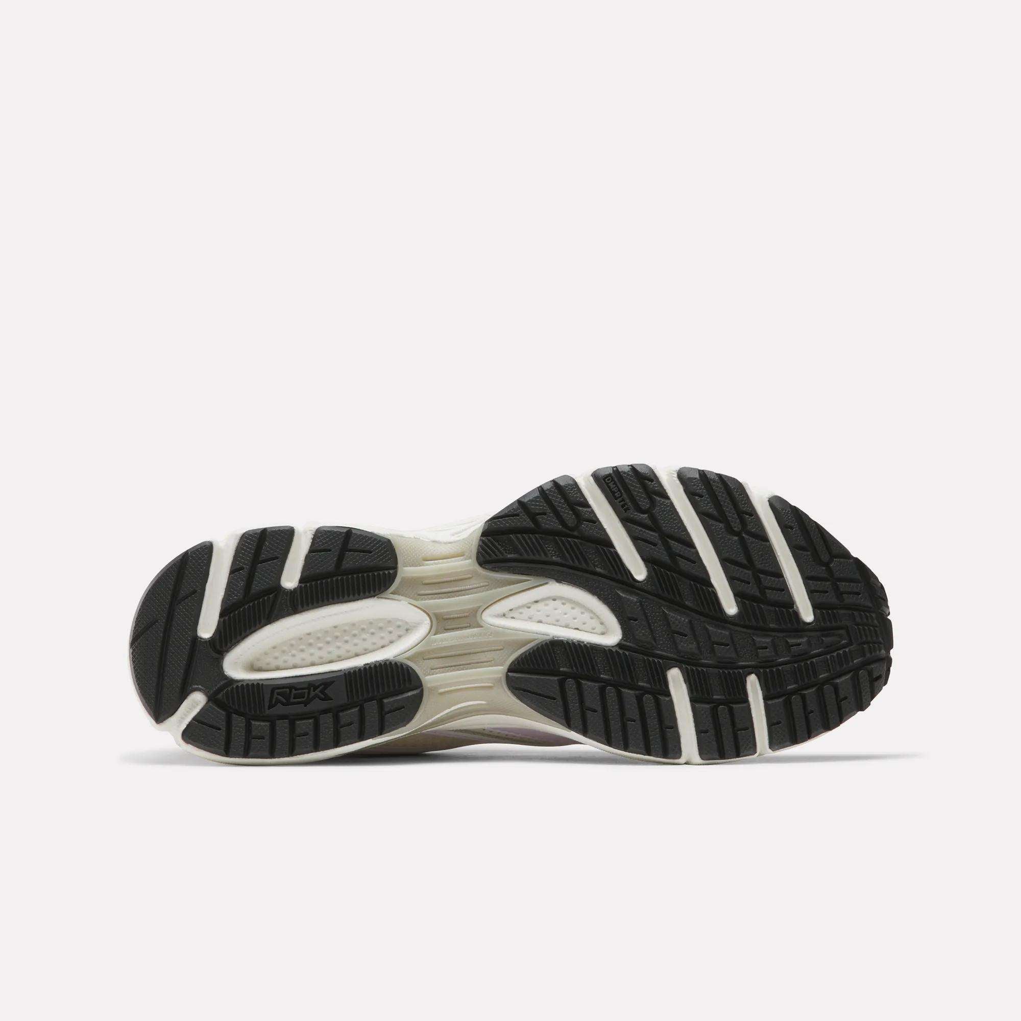 The image displays the black sole with white accents and textured tread of Reebok Women's Premier Trinity Shoes, highlighting their grip-focused design against a plain light background.