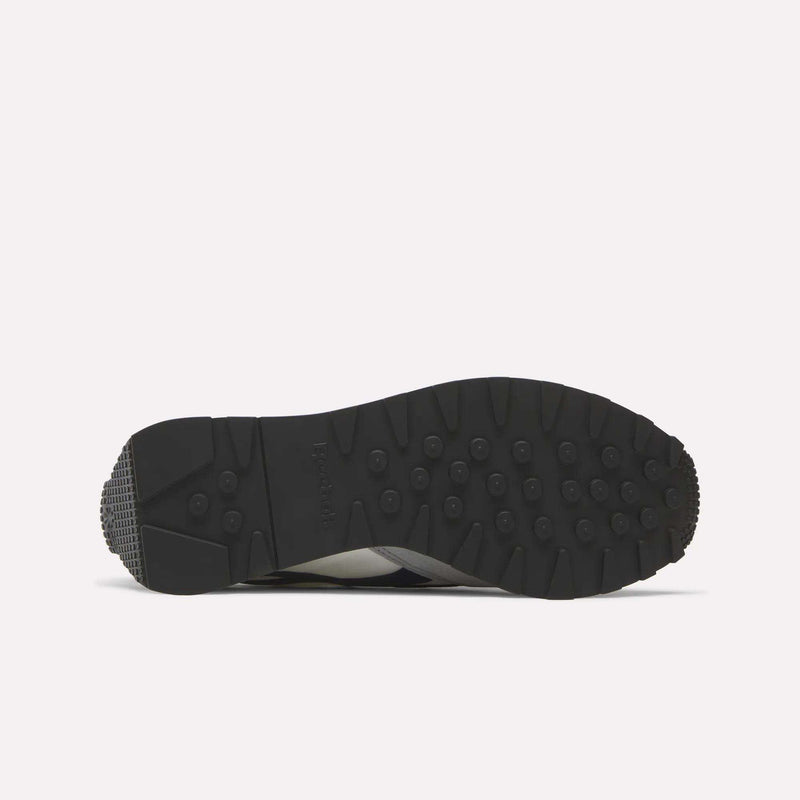 A black sole of the Reebok Aztec II Shoes displays a textured tread with round grips and a slightly raised heel, shown on a white background—classic elements inspired by retro running shoes and '80s marathon style.