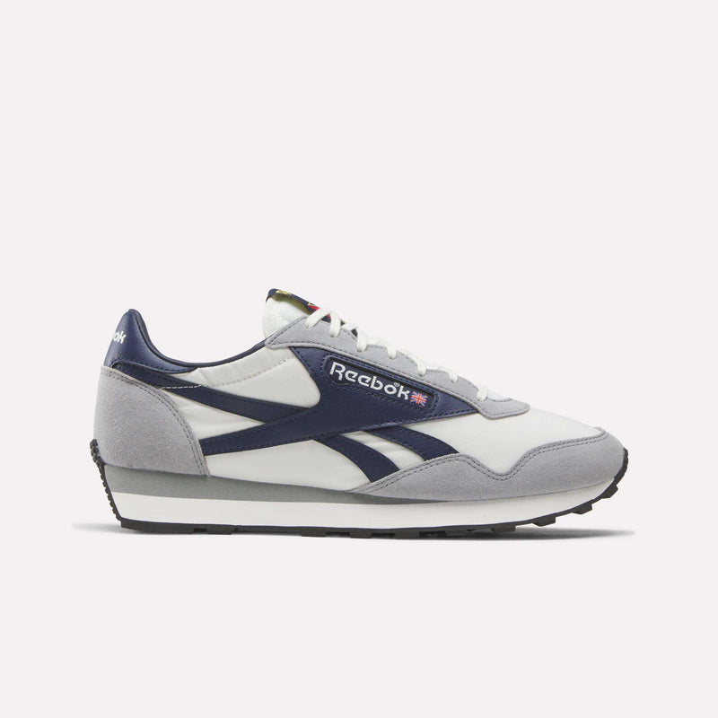 The Reebok Aztec II Shoes in white with navy and grey accents, Union Jack detail, and side branding evoke '80s marathon vibes and are shown from the left on a plain white background.