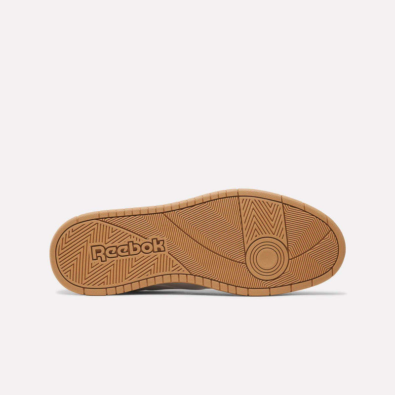 A tan rubber outsole featuring geometric tread patterns and the Reebok logo embossed near the heel, as seen from the bottom against a plain white background—a classic detail of the BB 1000 Shoes that reflects the ’80s heritage of iconic Reebok sneakers.