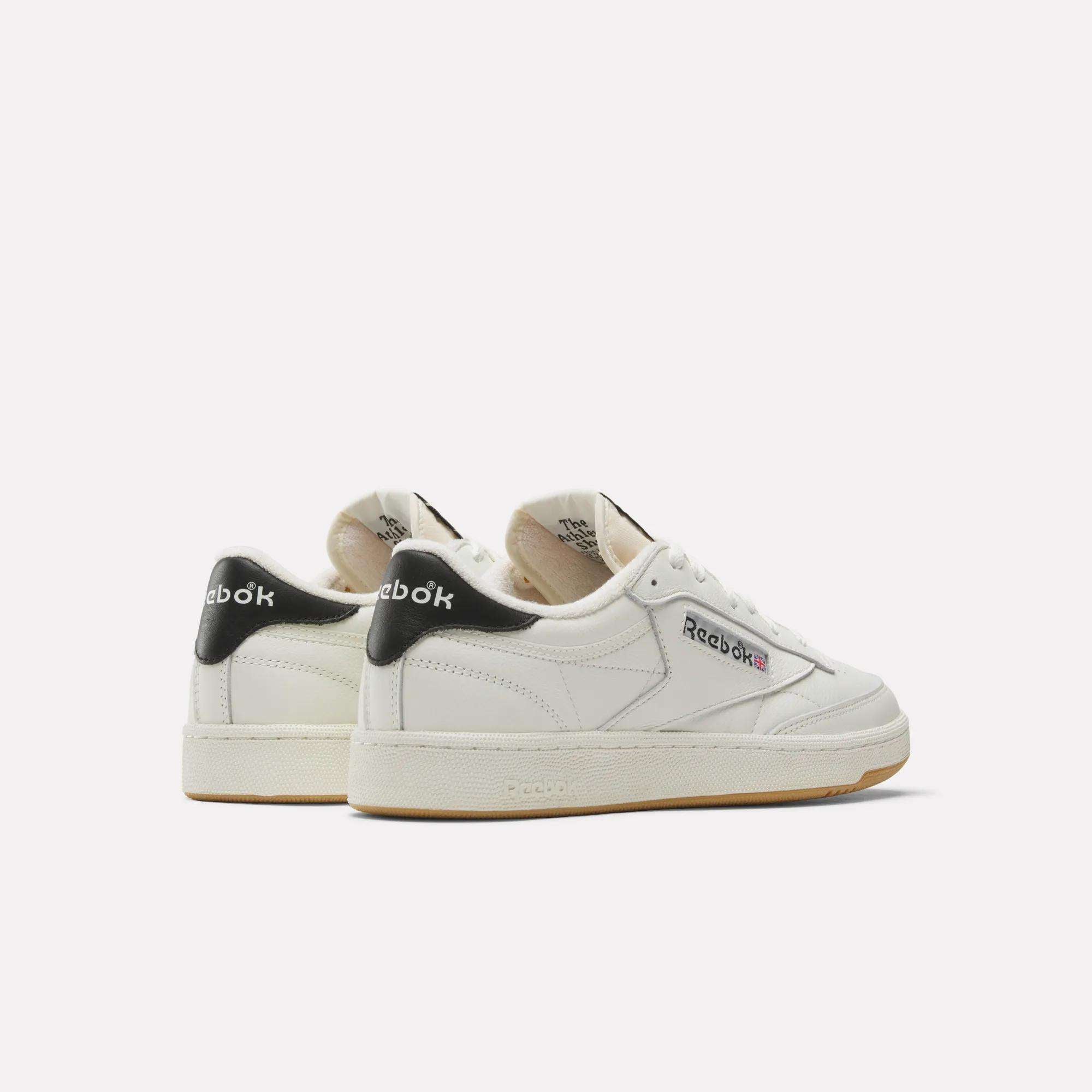 A pair of white Reebok Club C 85 Vintage Shoes with black heel accents, beige outsoles, and the Reebok logo on the sides. The durable leather upper is displayed at an angle, showing both the side and back.